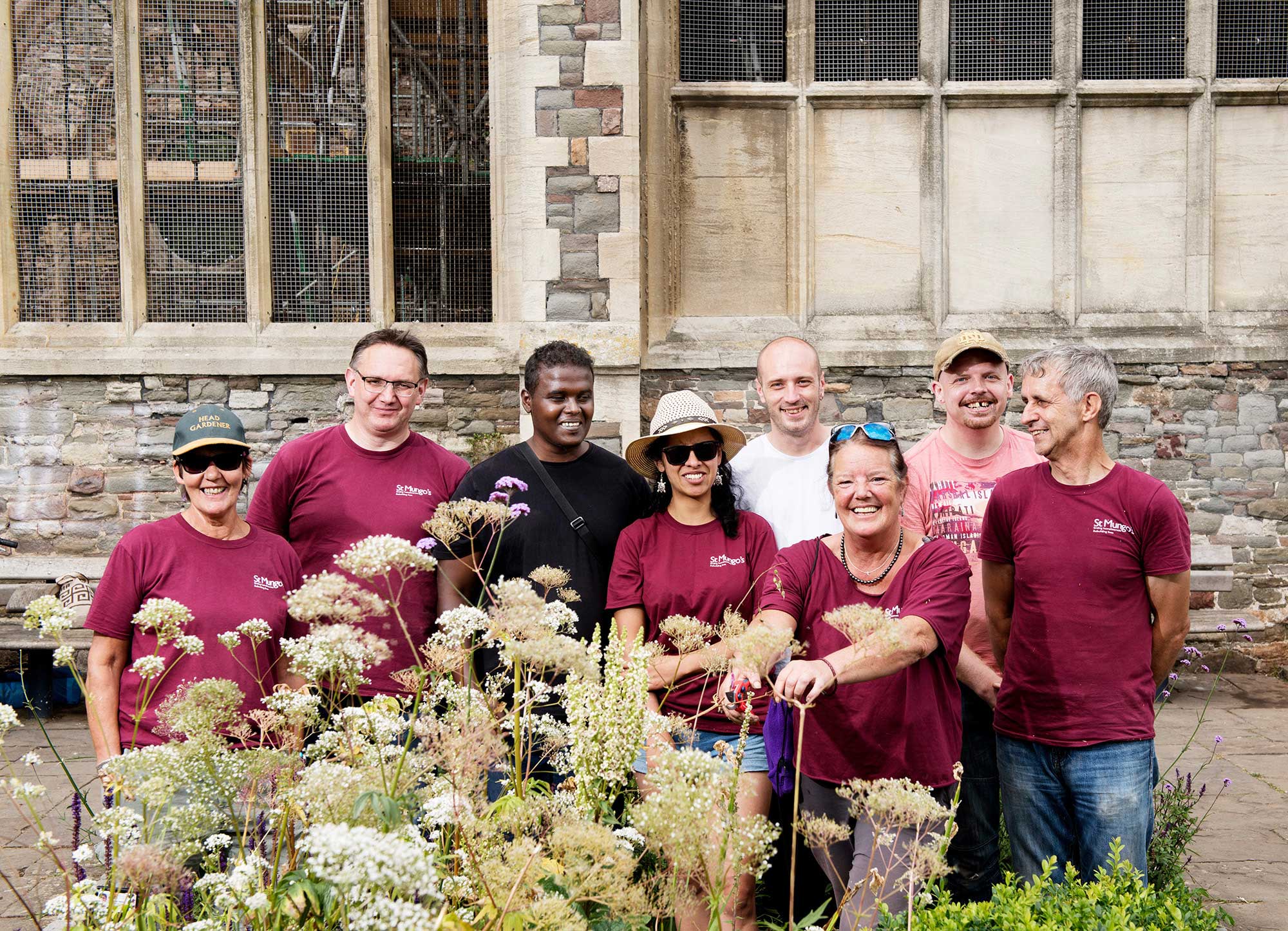 Group of people standing in front of church building with plants in front of them