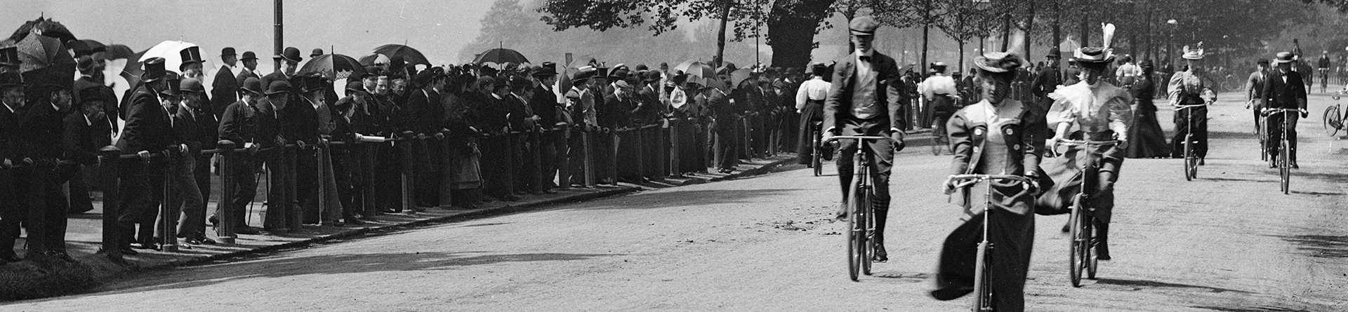 Archive photograph of male and female cyclists in Hyde Park with spectators lining the route.