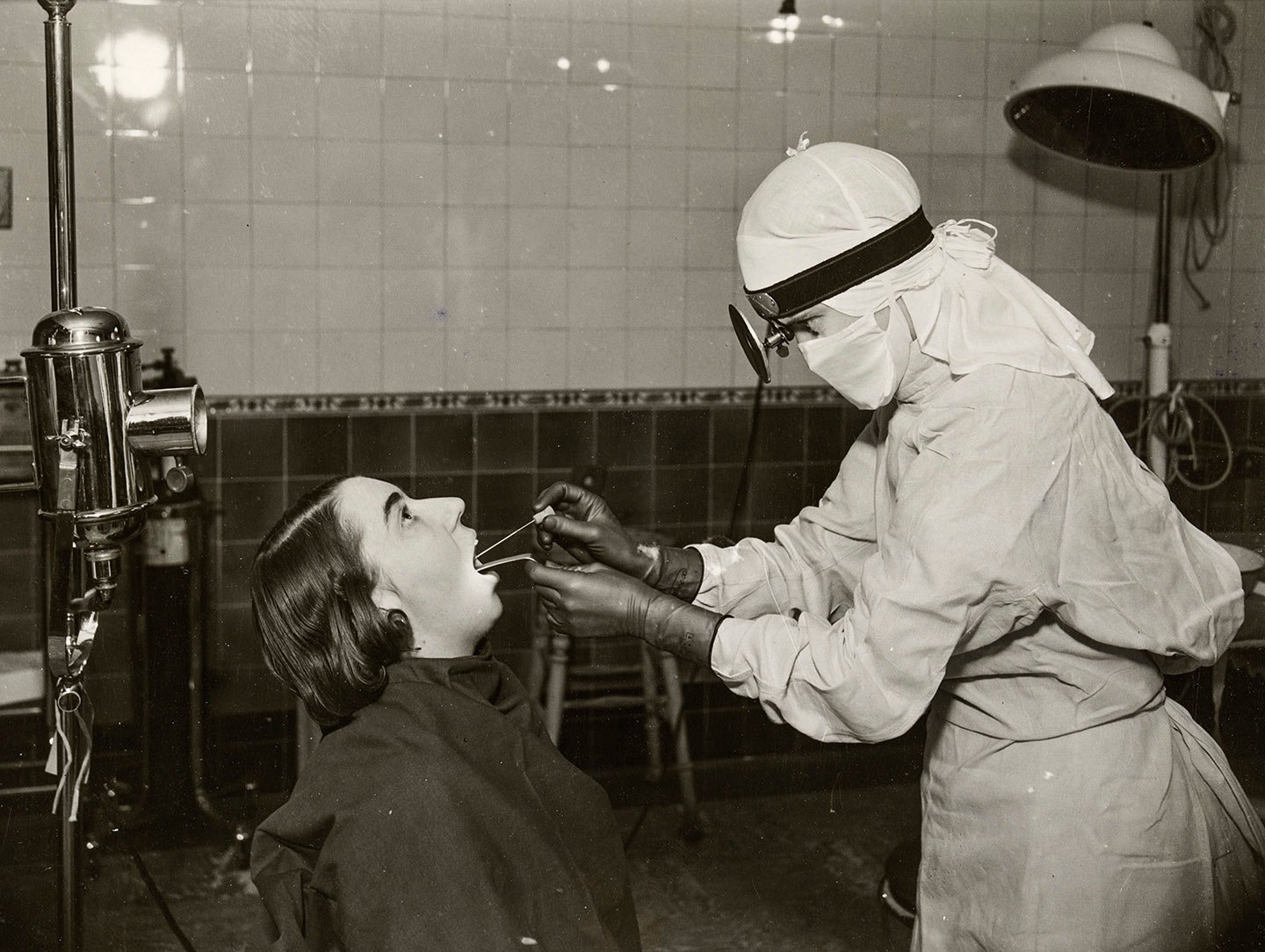 A nurse, aseptically garbed, taking a throat swab