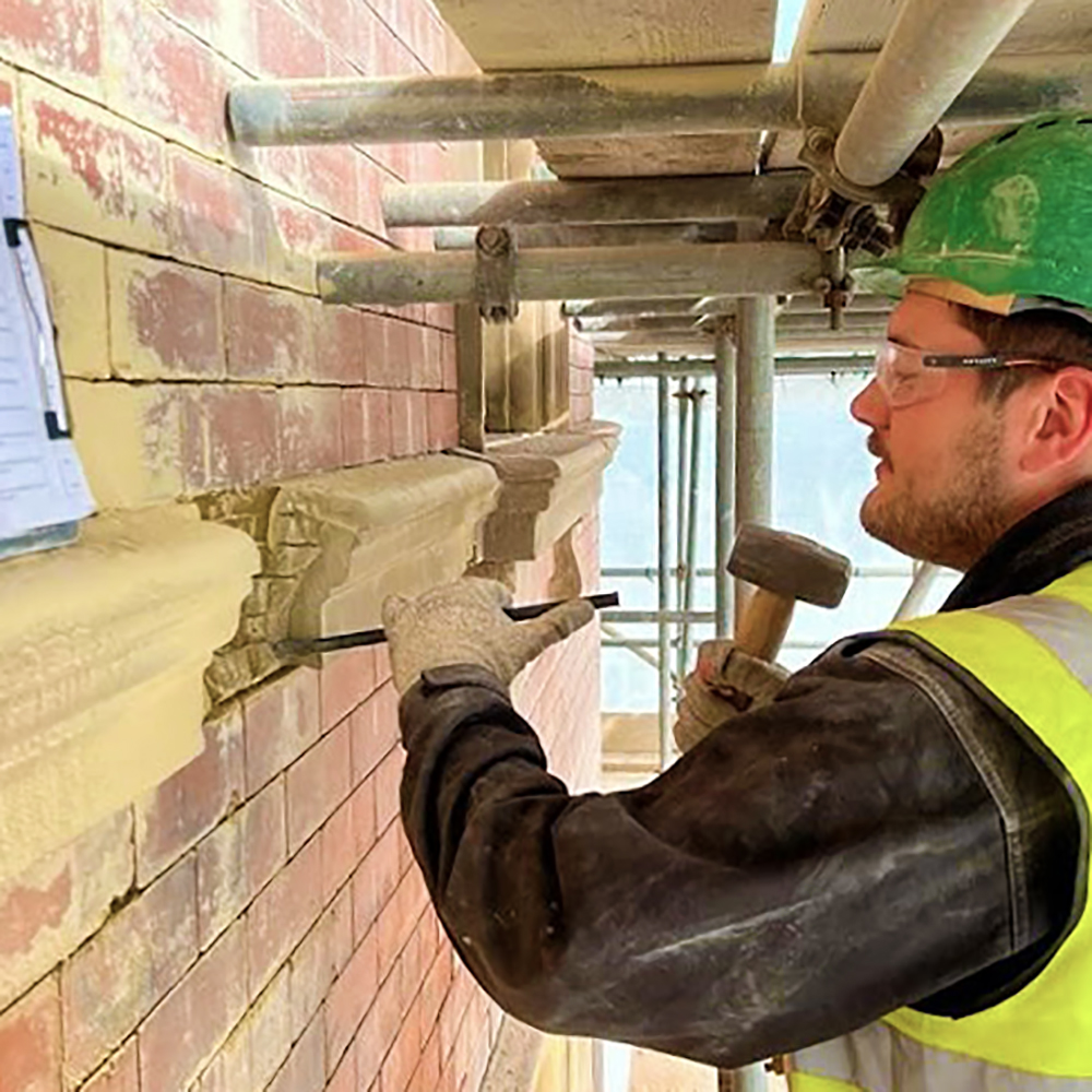 Apprentice Matthew Tinsley removes old masonry from a historic building.