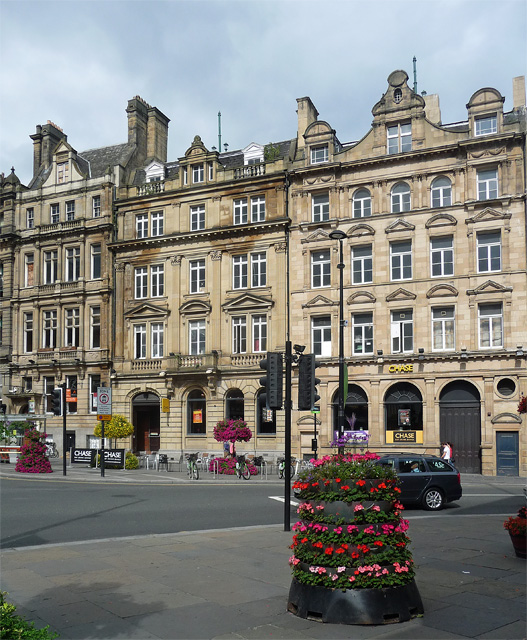 General view of a street scene featuring a row of terraced listed buildings in Newcastle, UK.