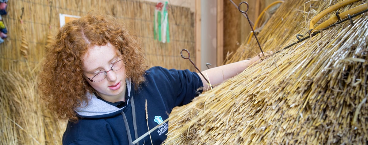 An image of King's Foundation trainee Miriam Johnson, learning traditional methods of thatching, as part of her bursary placement on the Building Craft Programme