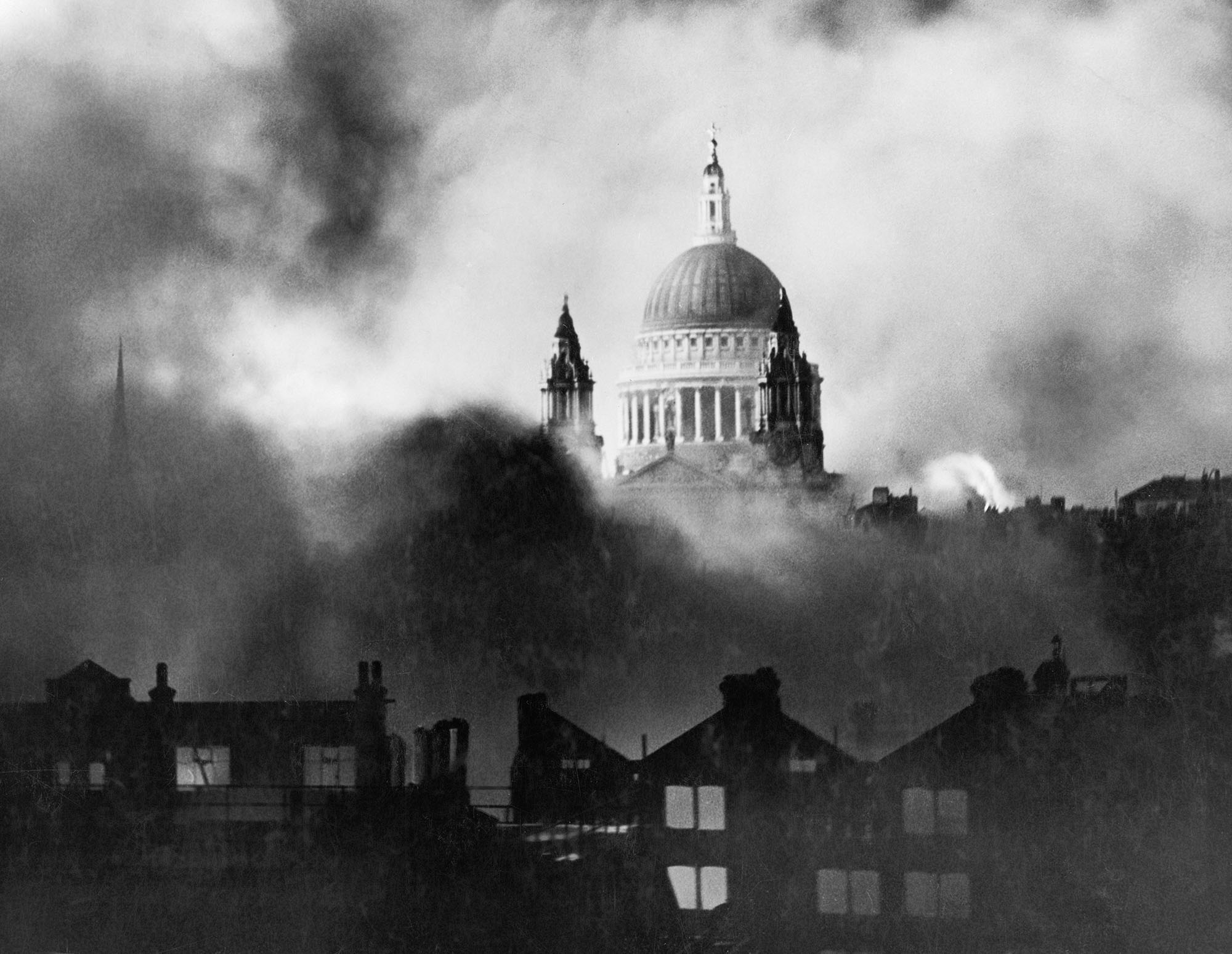 The dome of St Paul's emerging out of a cloud of smoke that engulfs burning buildings in the foreground.