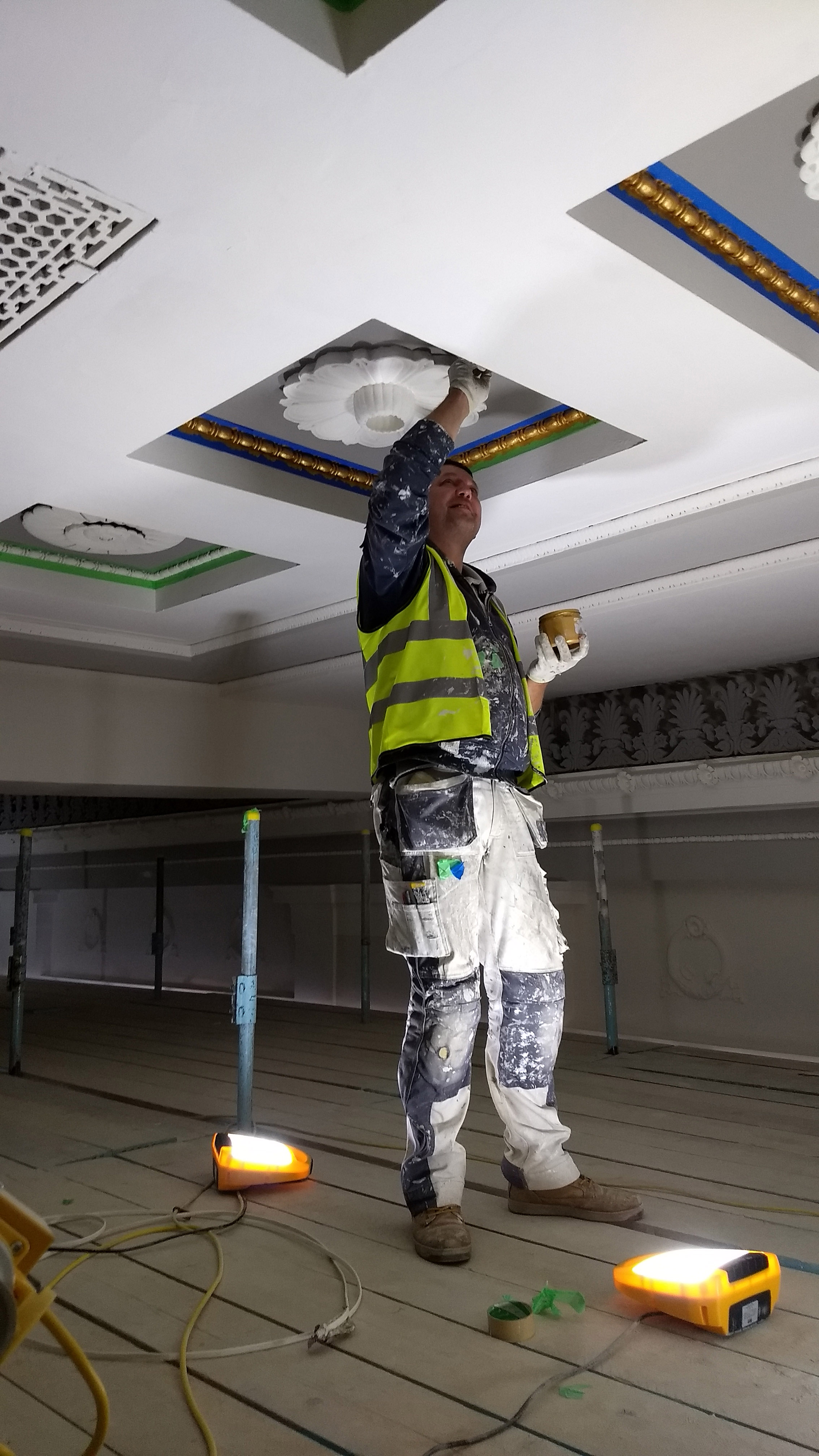 Photo of a painter touching up the ceiling using yellow paint