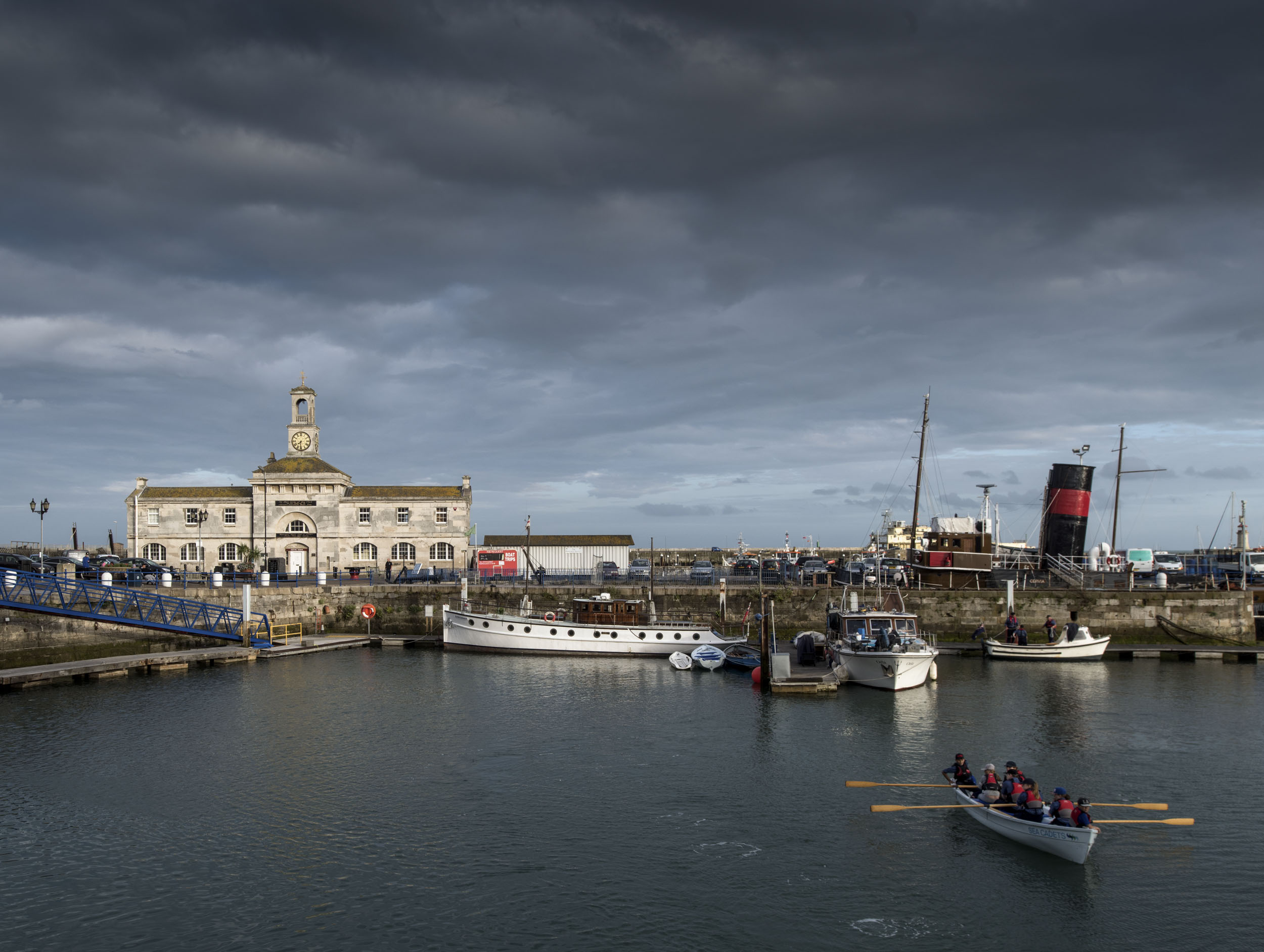 View across Yacht Marina with sea cadets in foreground and the Clock house in the background
