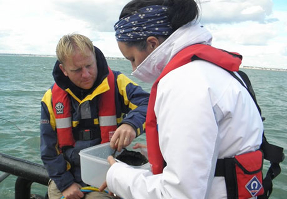 English Heritage marine archaeologist Mark Dunkley with a member of the team inspecting an artefact on deck