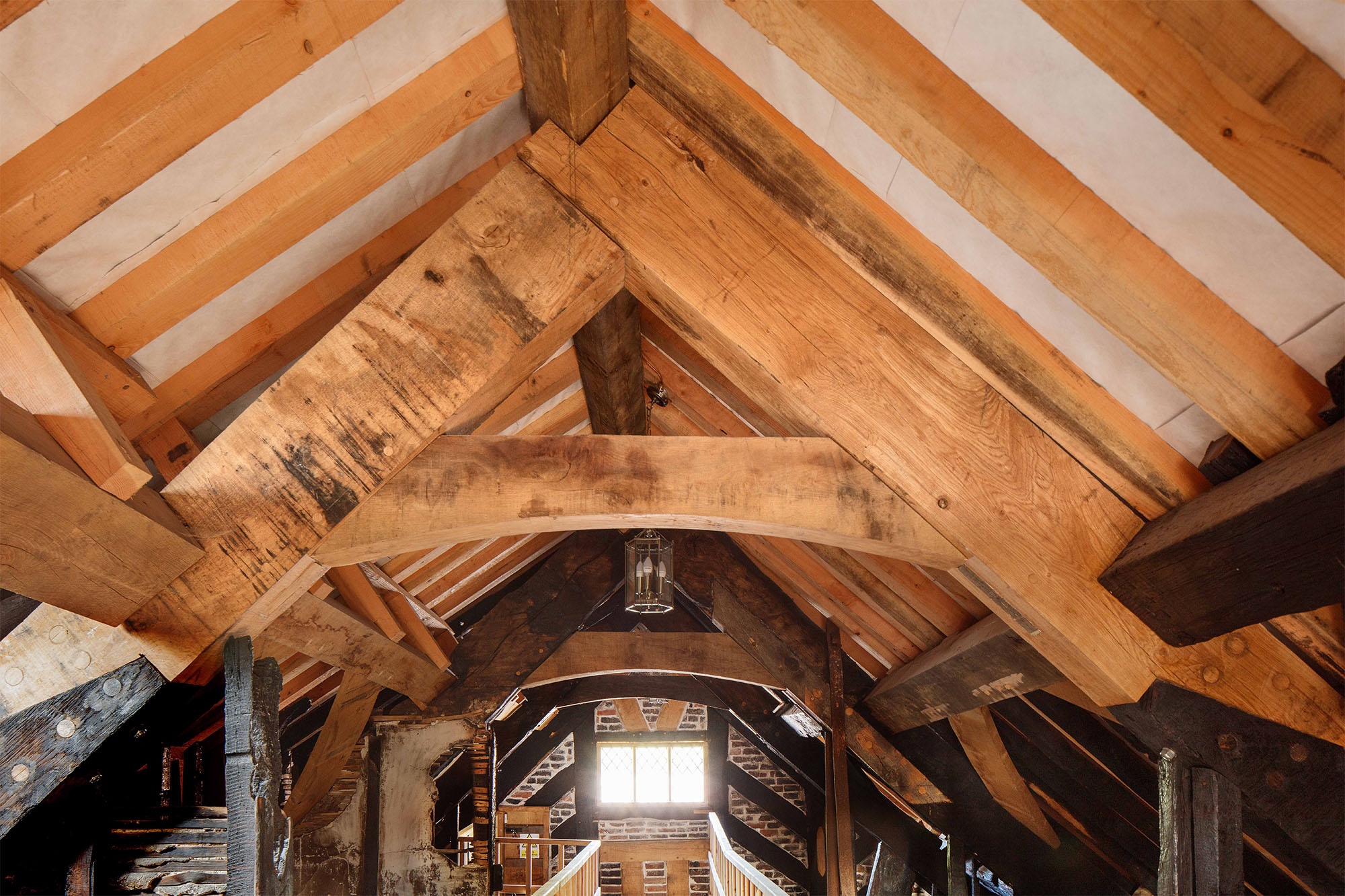 Wooden beams in a timber roof - some new, some blackened by fire.
