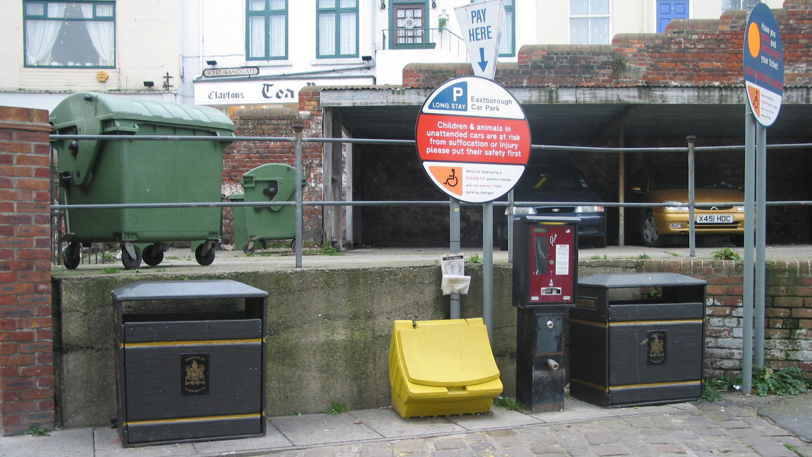 A cluster of bins, fences, signs poles and meters
