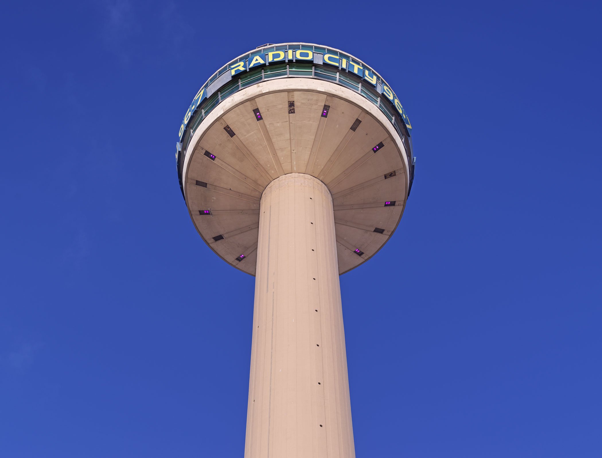 Photograph of the upper portion of a tall concrete radio tower with a circular viewing platform at the top.