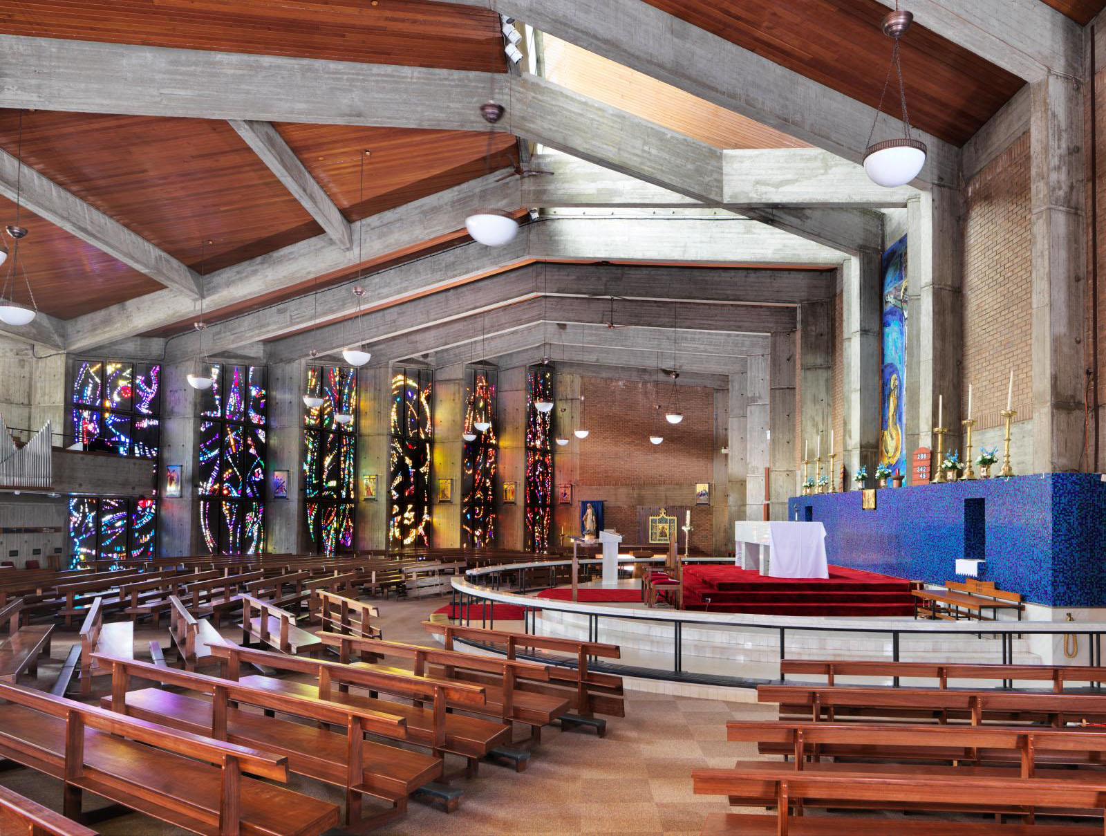 Image of the interior of St Jude's in Wigan showing the modern pews and stained glass windows.