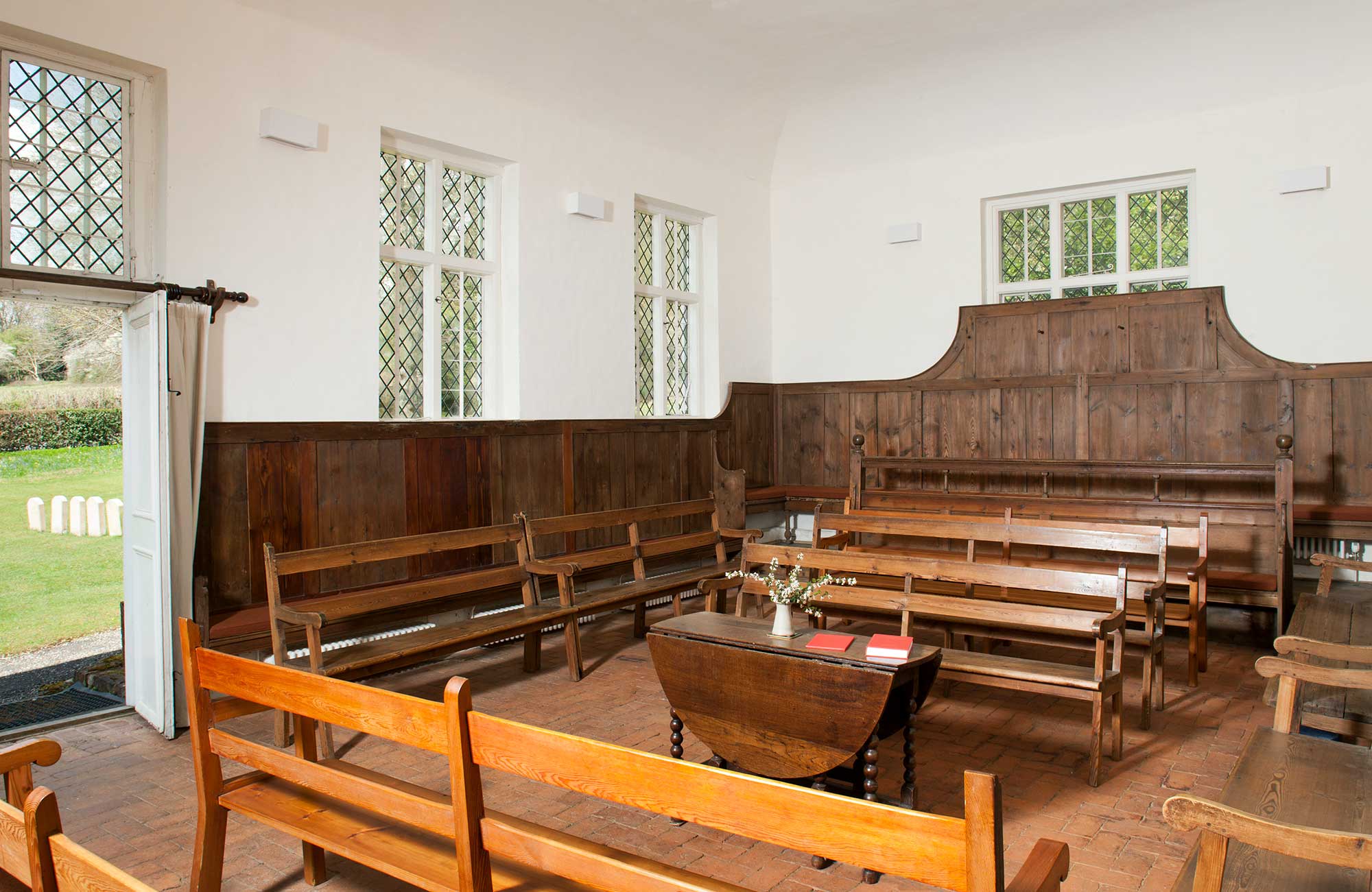 Interior of meeting house with wooden benches arranged around a table