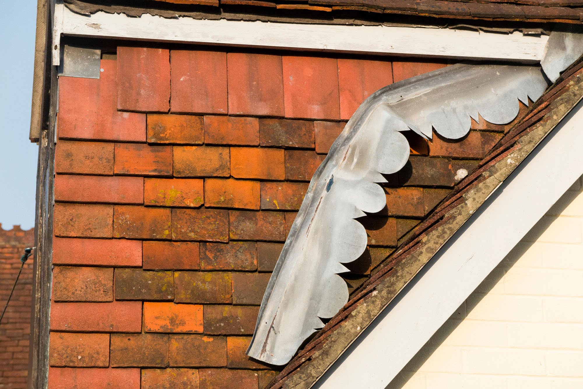 A section of lead flashing which is detached from the roof and has dropped down, only being held in place at one end.