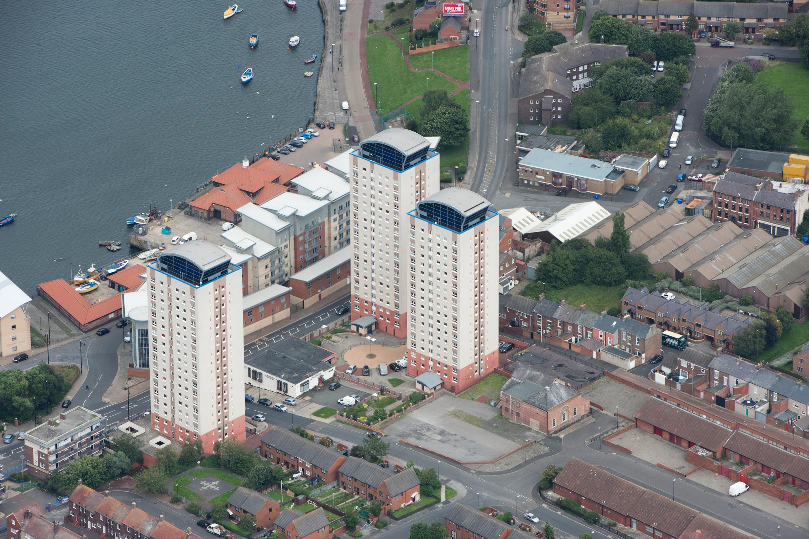 Aerial view of Phoenix Hall and three nearby tower blocks in Sunderland. The top left corner shows the shoreline and boats.