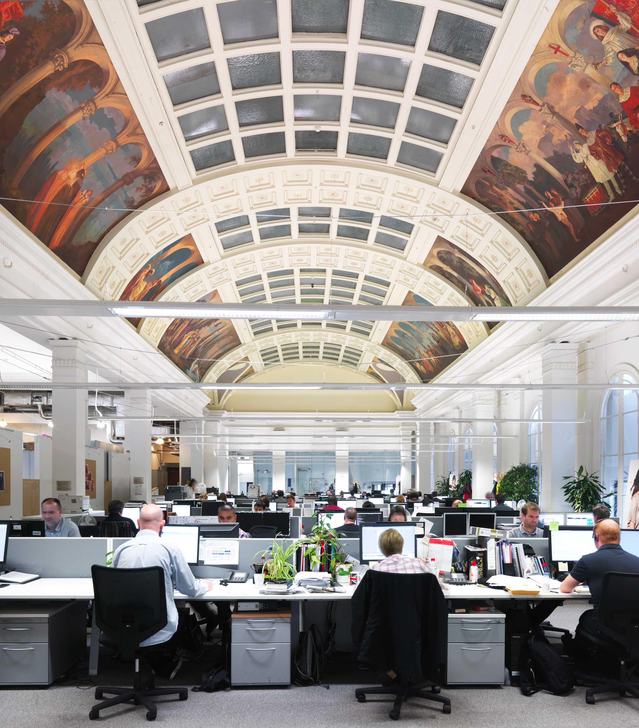 People working in an IT office with an elaborate historic ceiling.