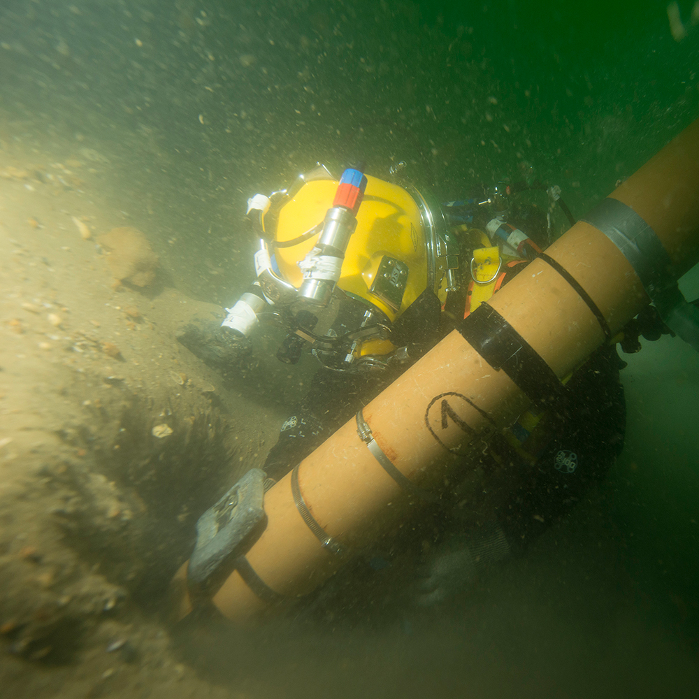 Diver holds a tube that is removing sand from the surface of the 'Rooswijk' wreck.