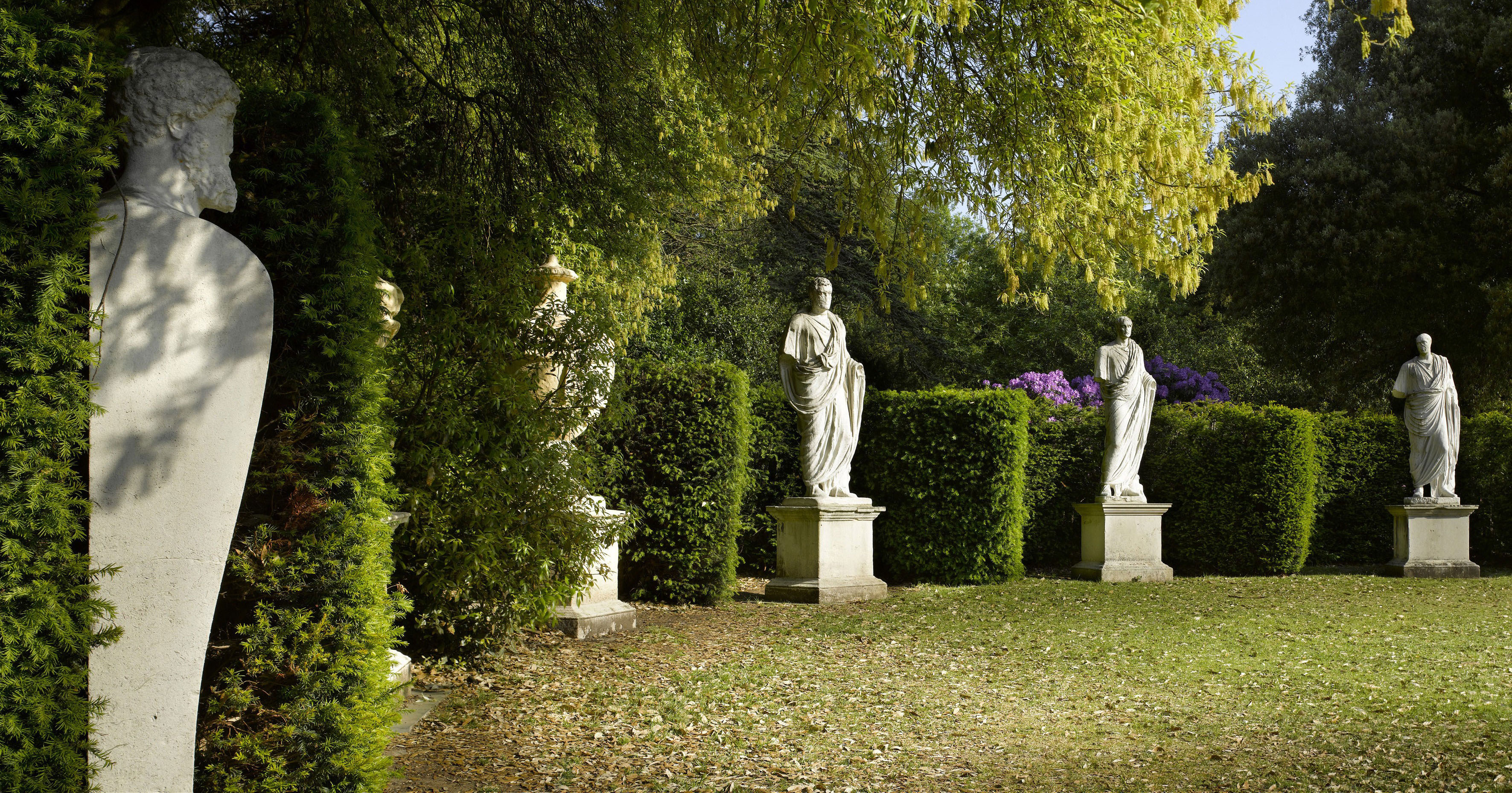 A semi-circle of yew hedging with niches containing statuary and sphinxes.