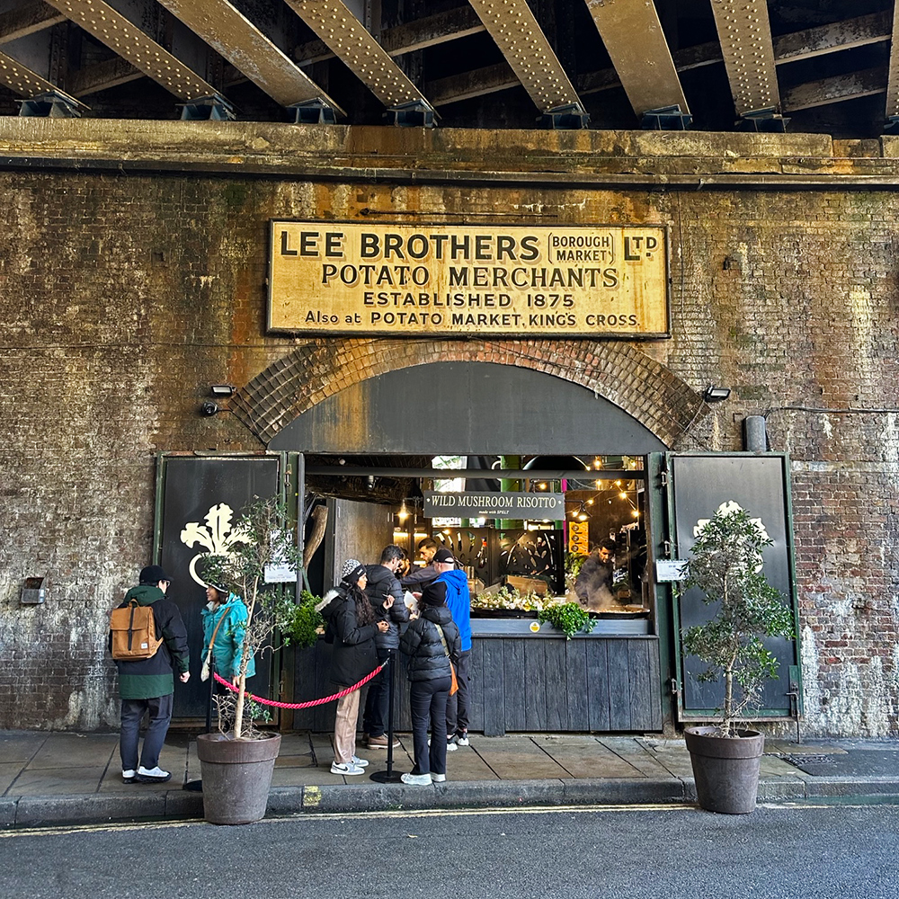 A photograph of a food market stall with a historic ghost sign above it. 