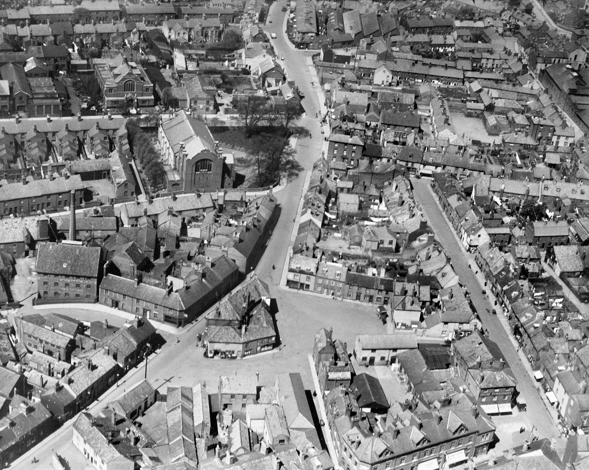 Photo shows a black and white aerial photo of residential, religious and industrial buiildings