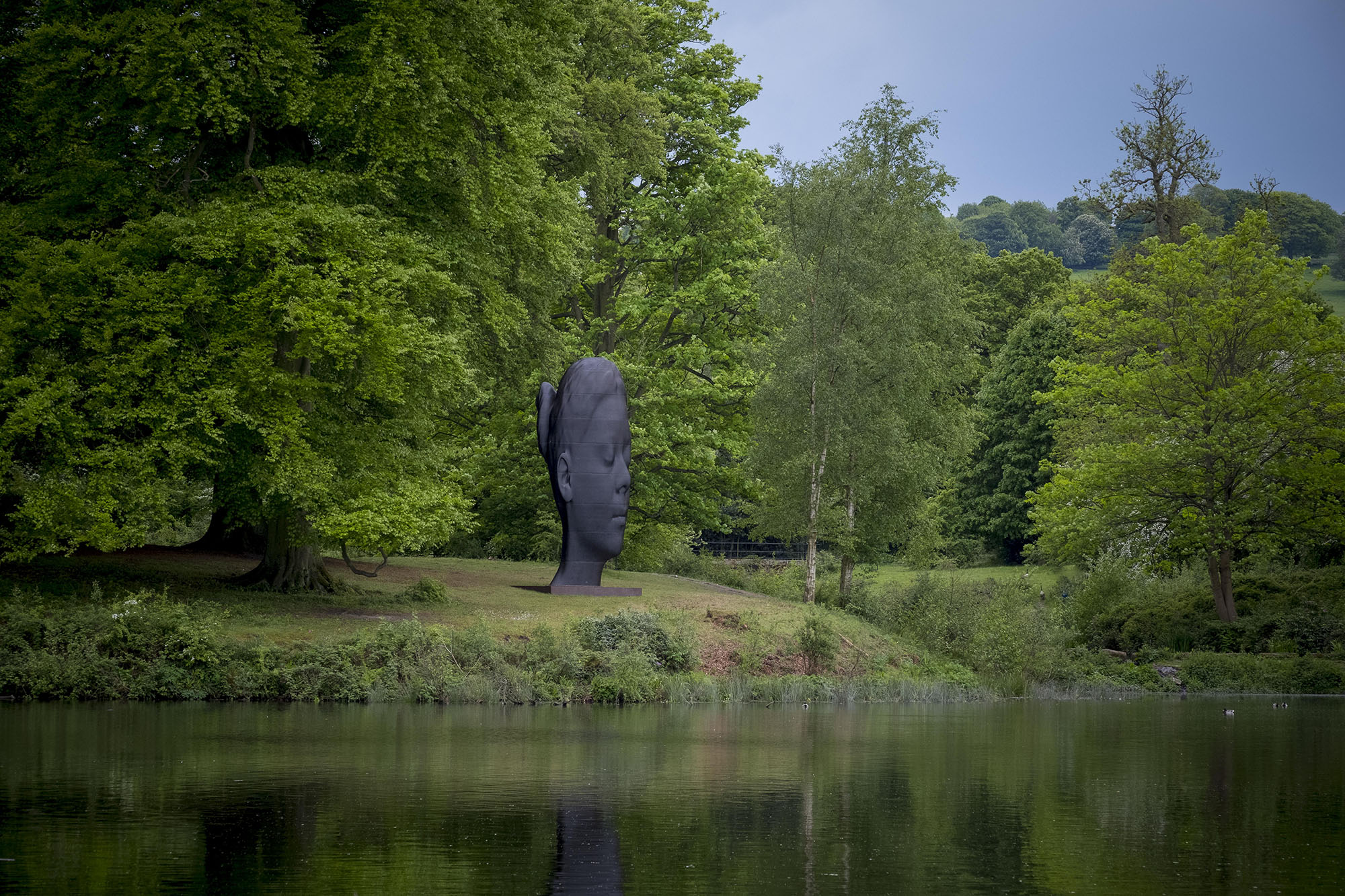 Large sculpture of woman's head looking out over a lake