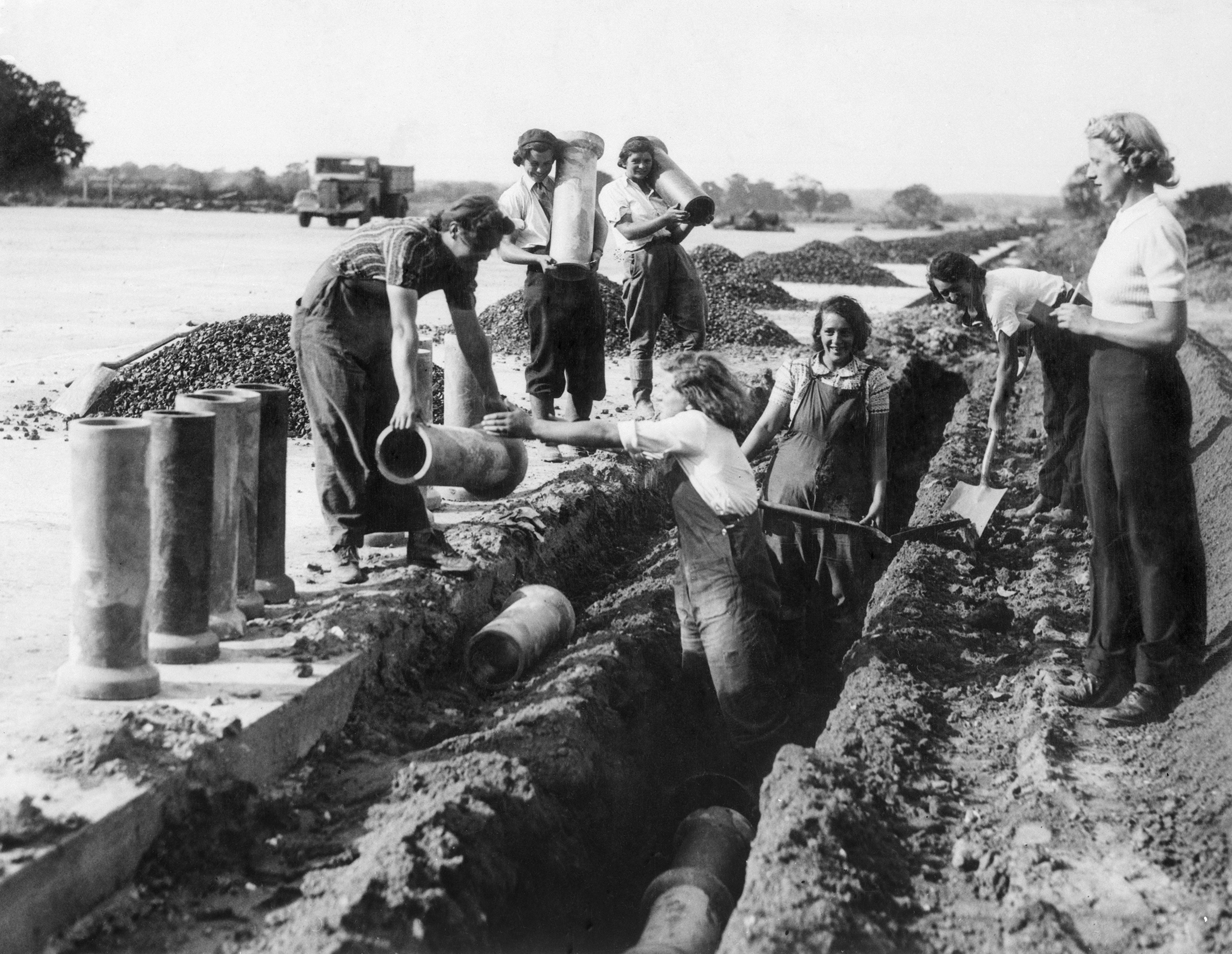 Black and white image of female construction workers laying pipes during Second World War