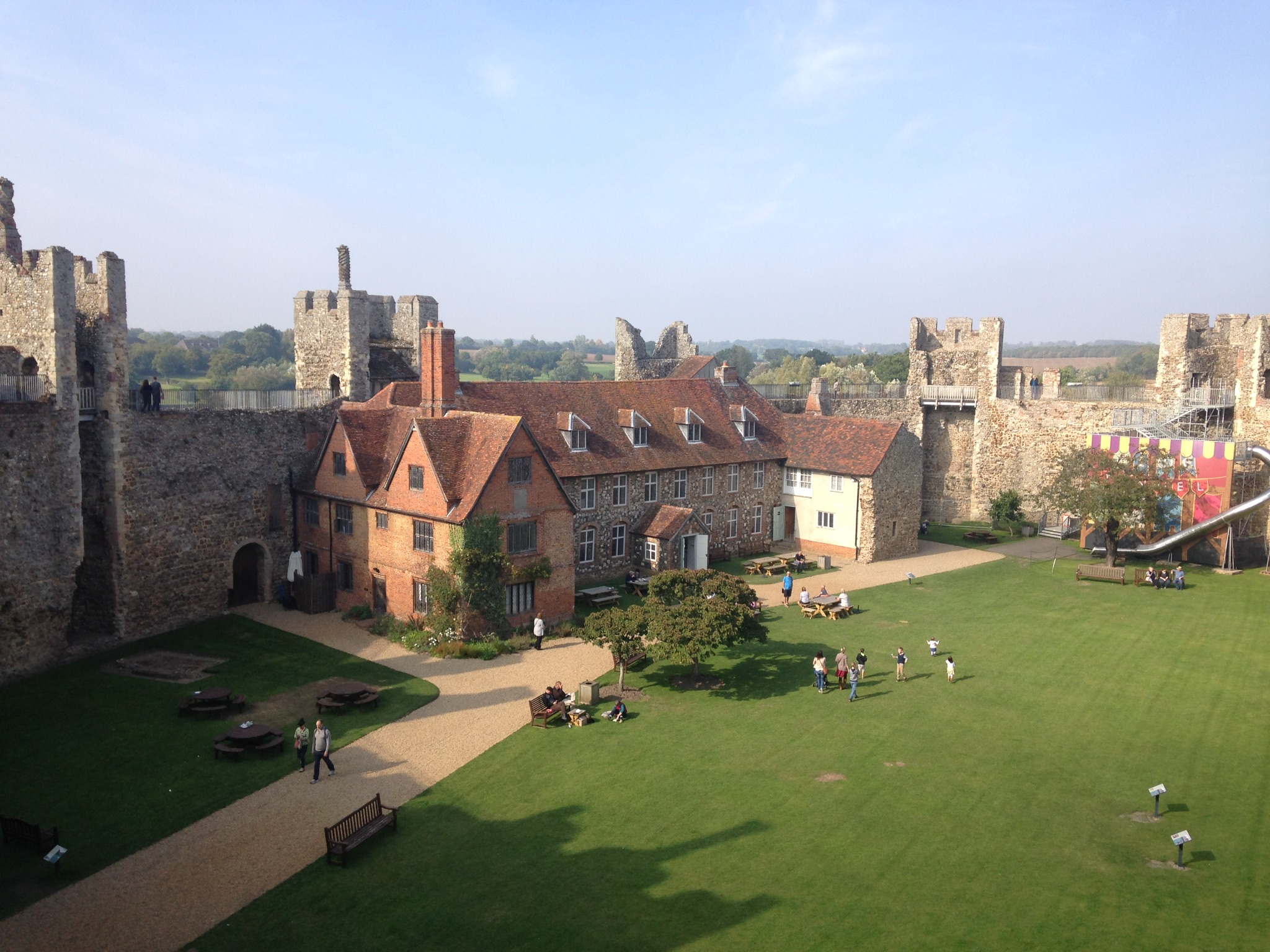 Framlingham Castle with members of the public including children playing in sunshine on lawns in the foreground