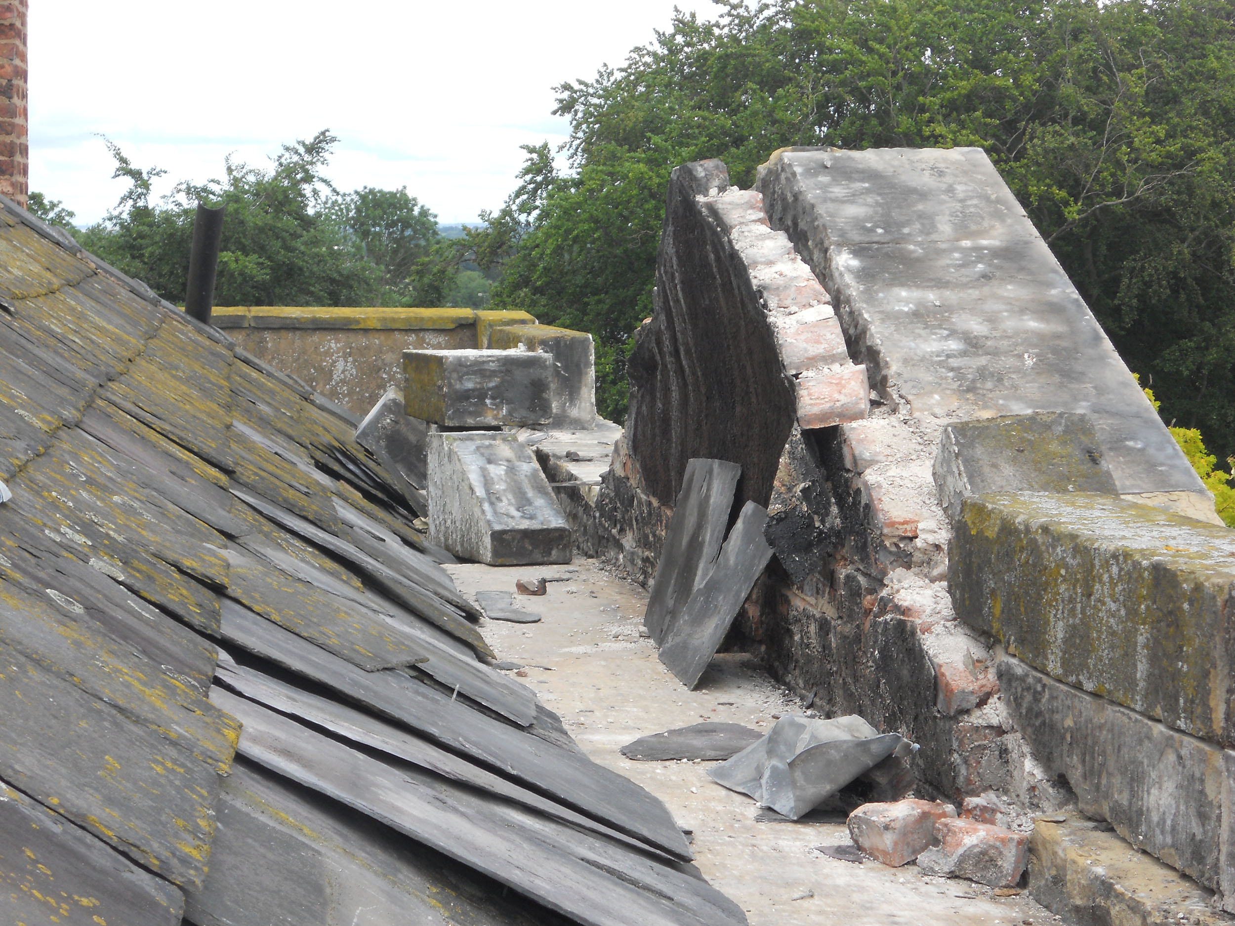 Damaged tiles, brickwork and gutter up on the roof of Tarvin Hall, Cheshire.