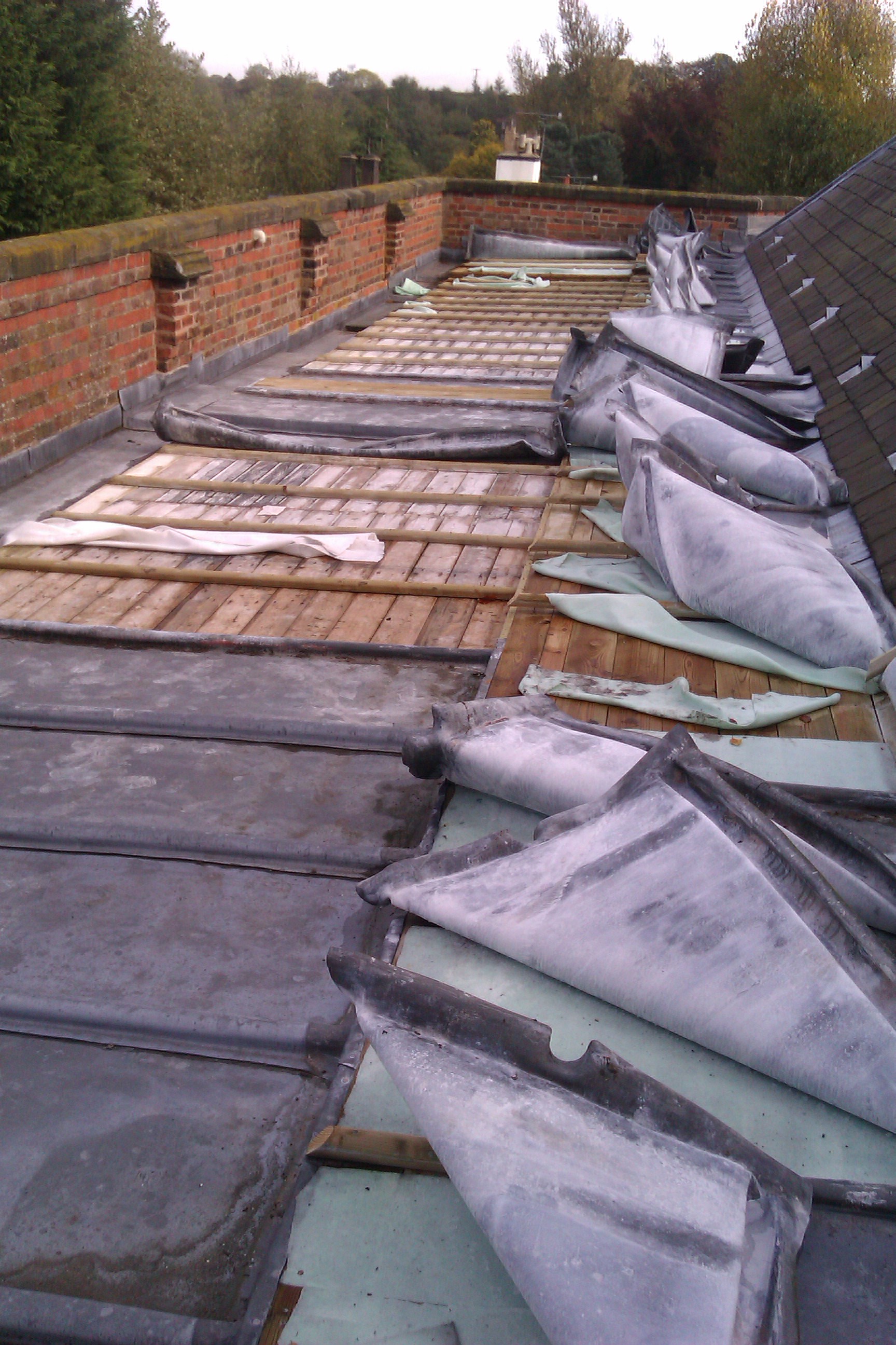 Wooden boards laid bare and peeled back lead sheeting up on a church roof where thieves have attempted to steal the lead.