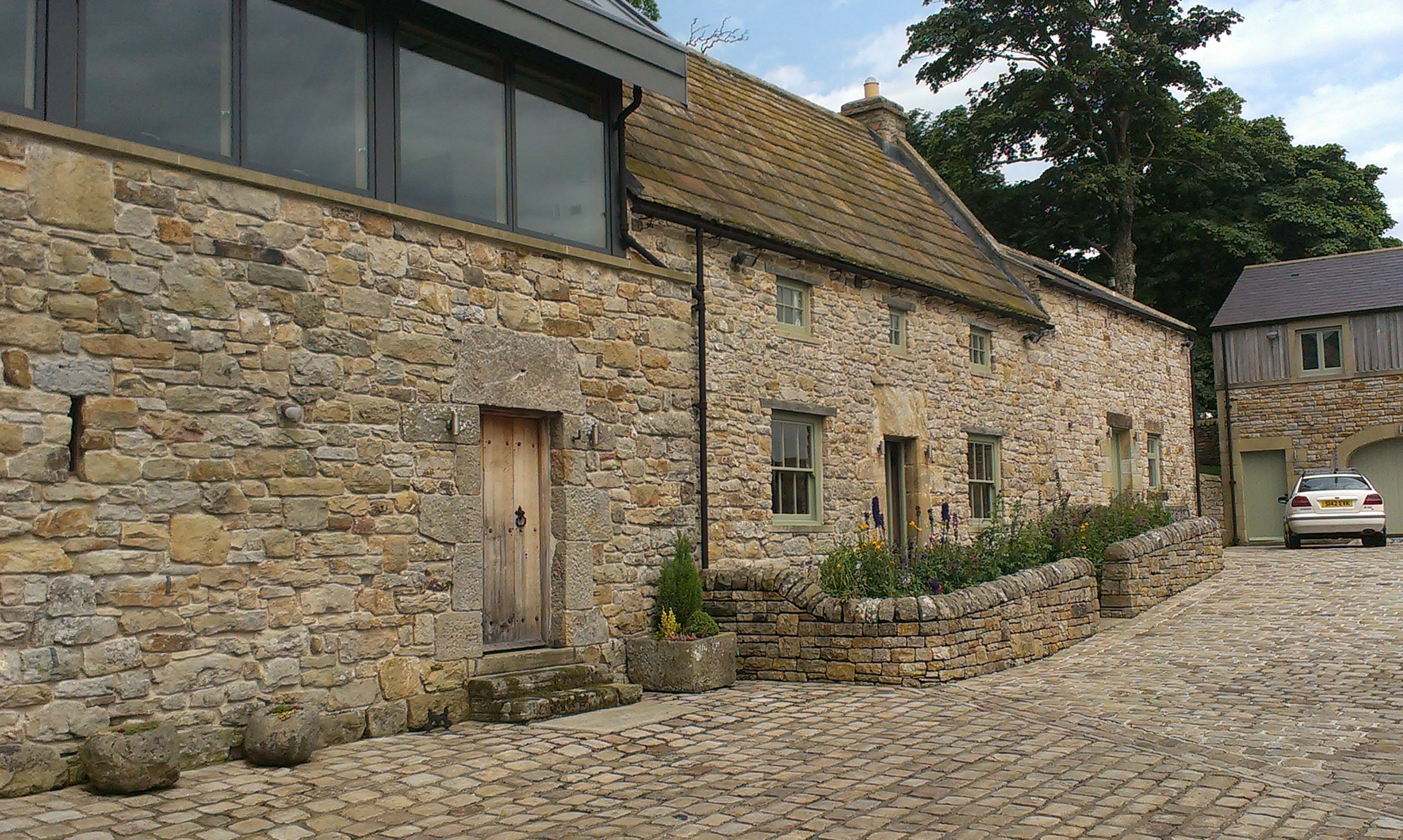 Stone farm building conversion and cobbled foreground.