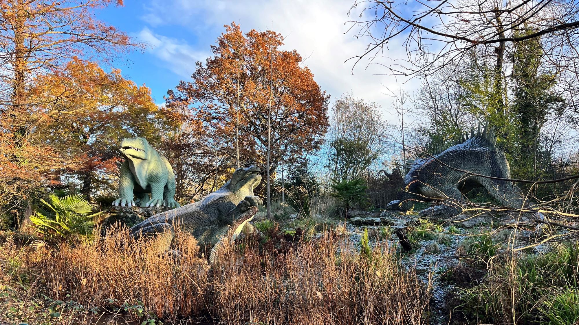 Photograph of three large Dinosaur sculptures in a wintry landscape.