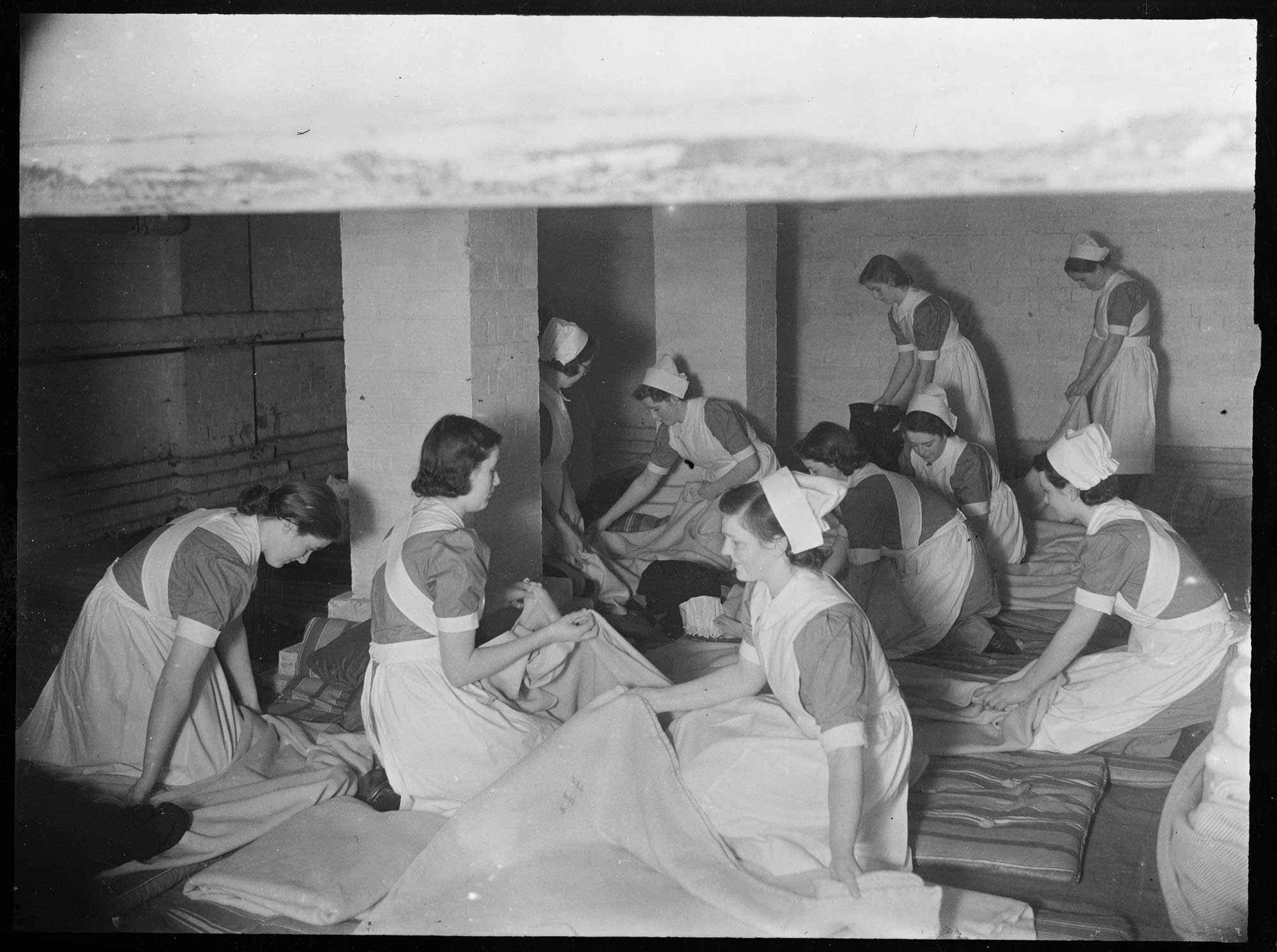 Nurses preparing bedding on the floor of an underground air raid shelter at Manchester Royal Infirmary