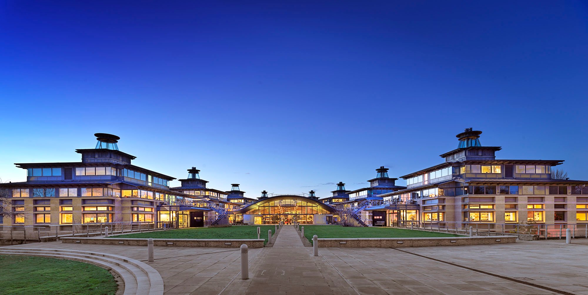 General view of the university mathematical sciences centre site illuminated at twilight, looking west towards the cafe and reception building and flanking pavilions