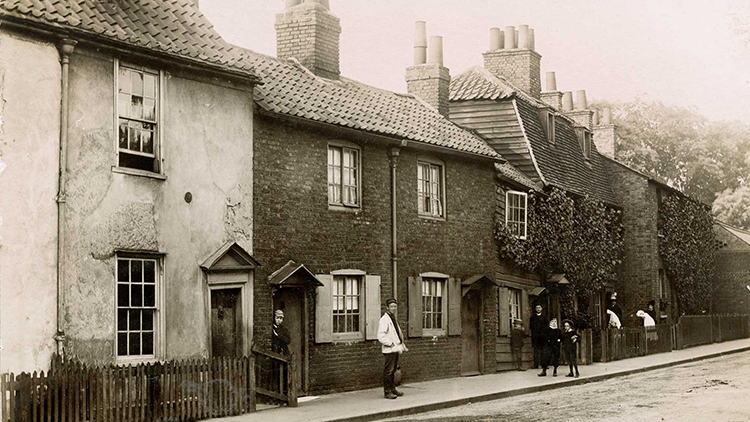 Sepia toned photo of people standing outside a row of houses.
