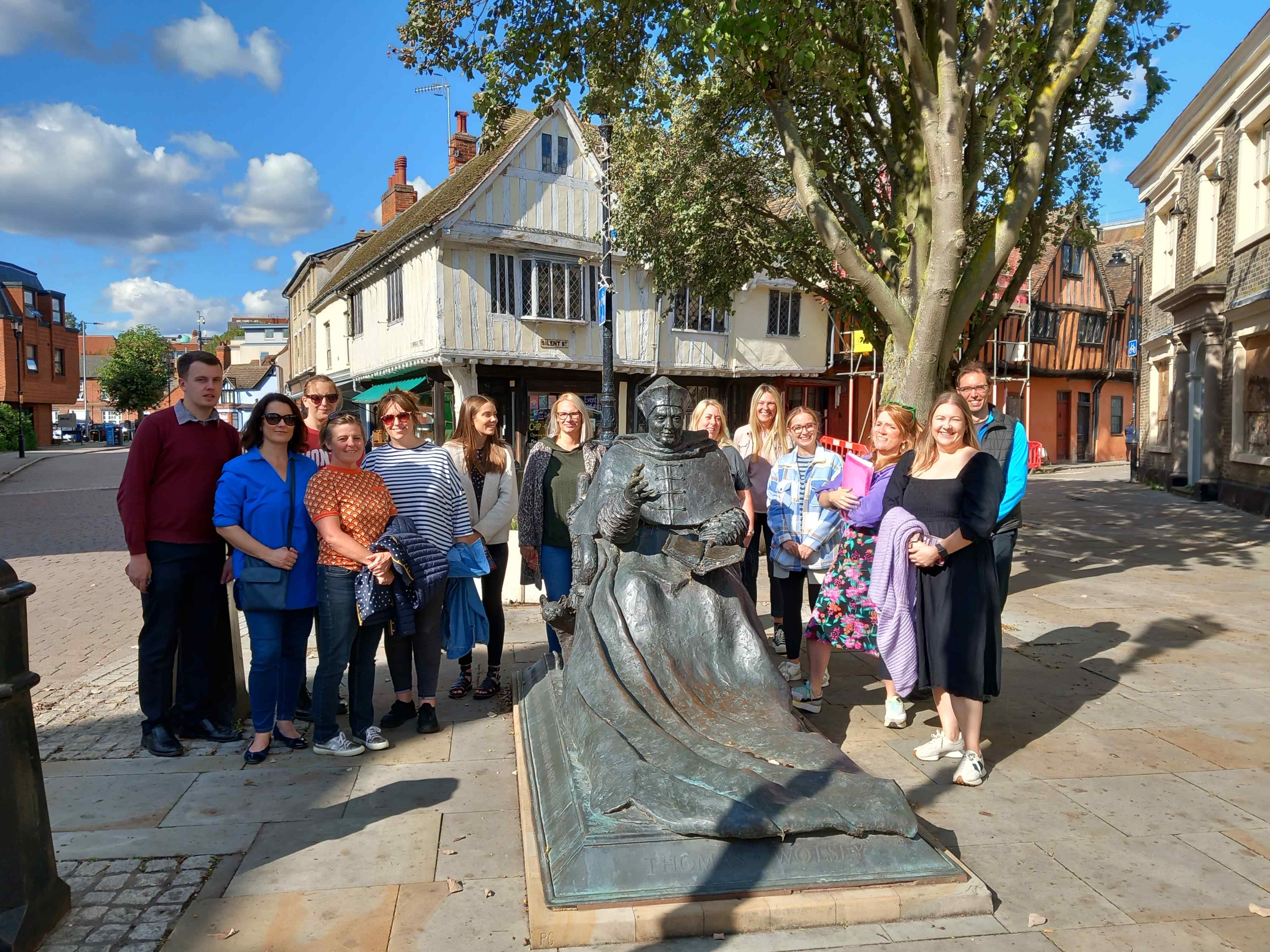 A group of teachers stand around a statue of Thomas Wolsey in Ipswich town centre.