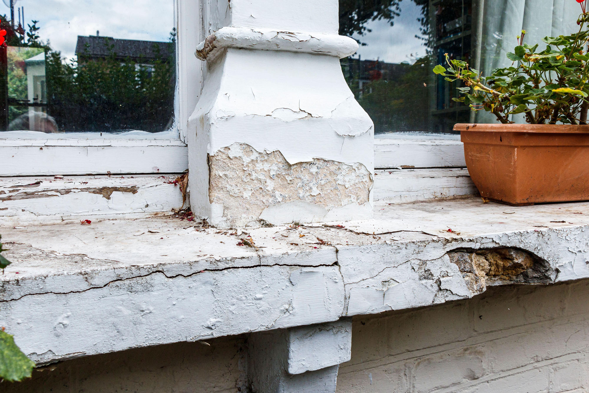 A wooden window frame and windowsill showing signs of decay. 