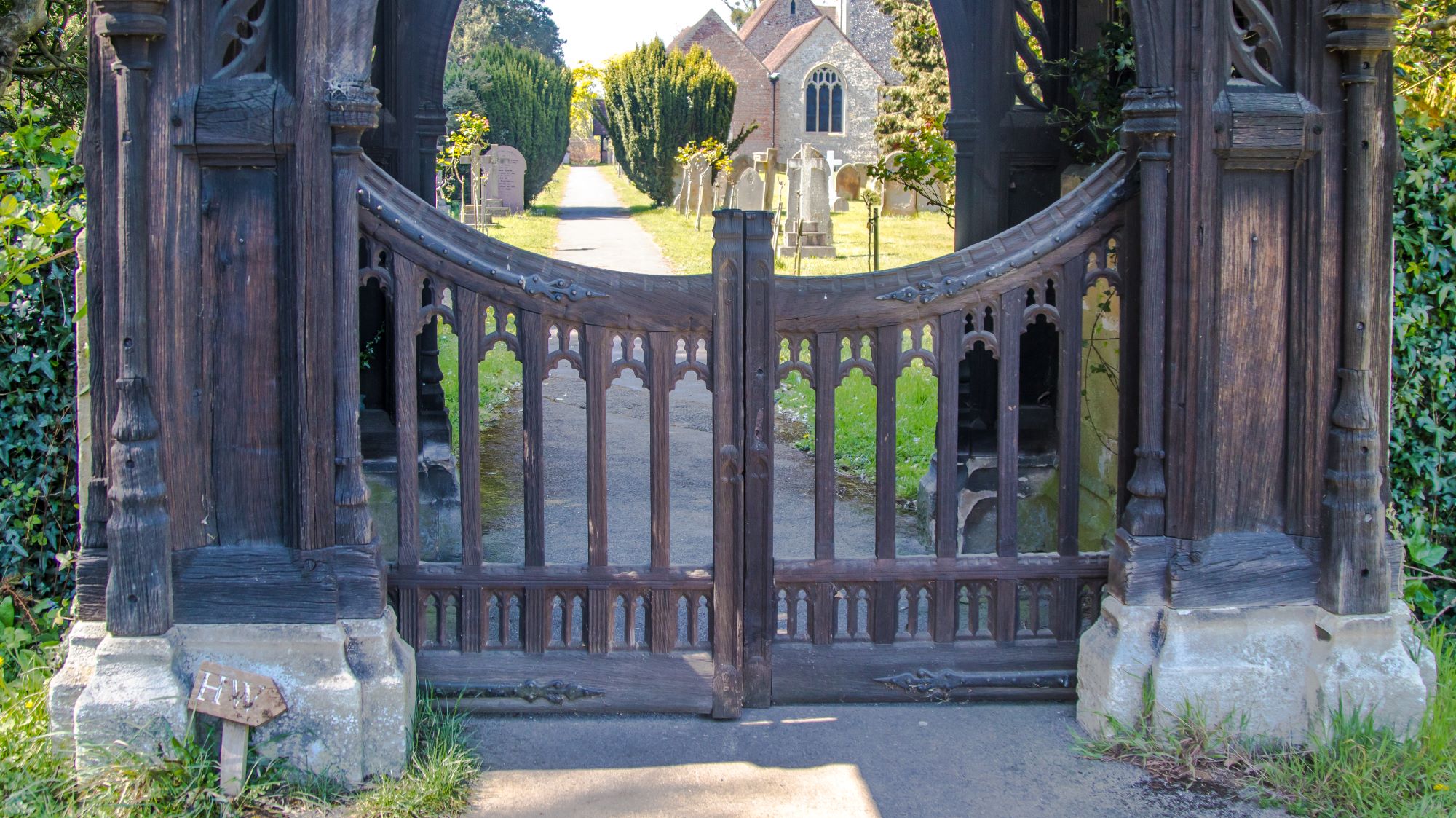 Decorative carved wooden gateway leading towards a church.