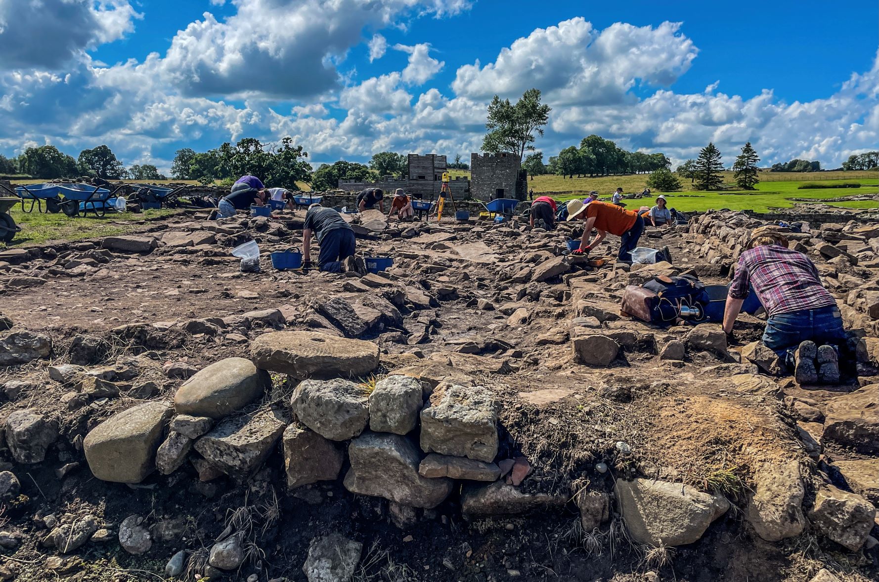 People on their knees digging at an archaeological site.