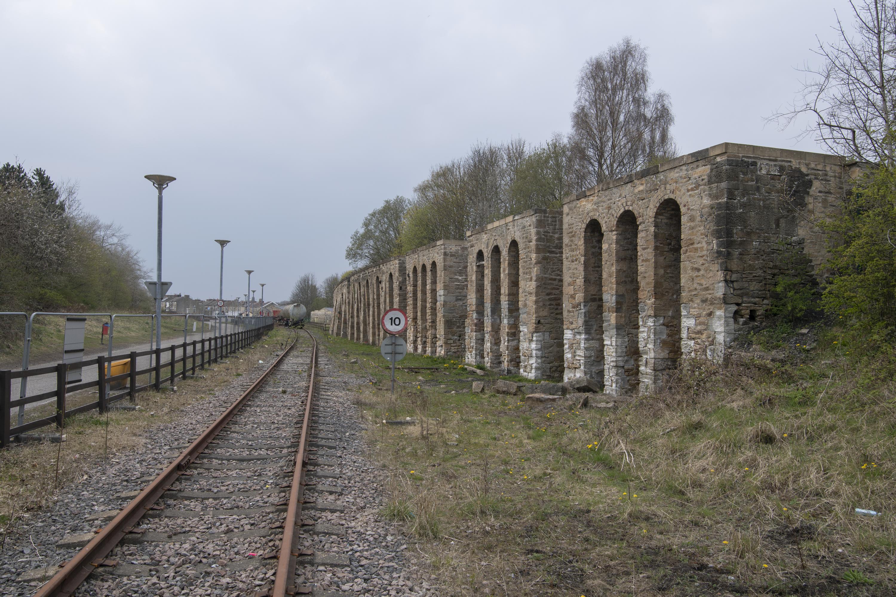 A series of stone arches next to a railway line. 