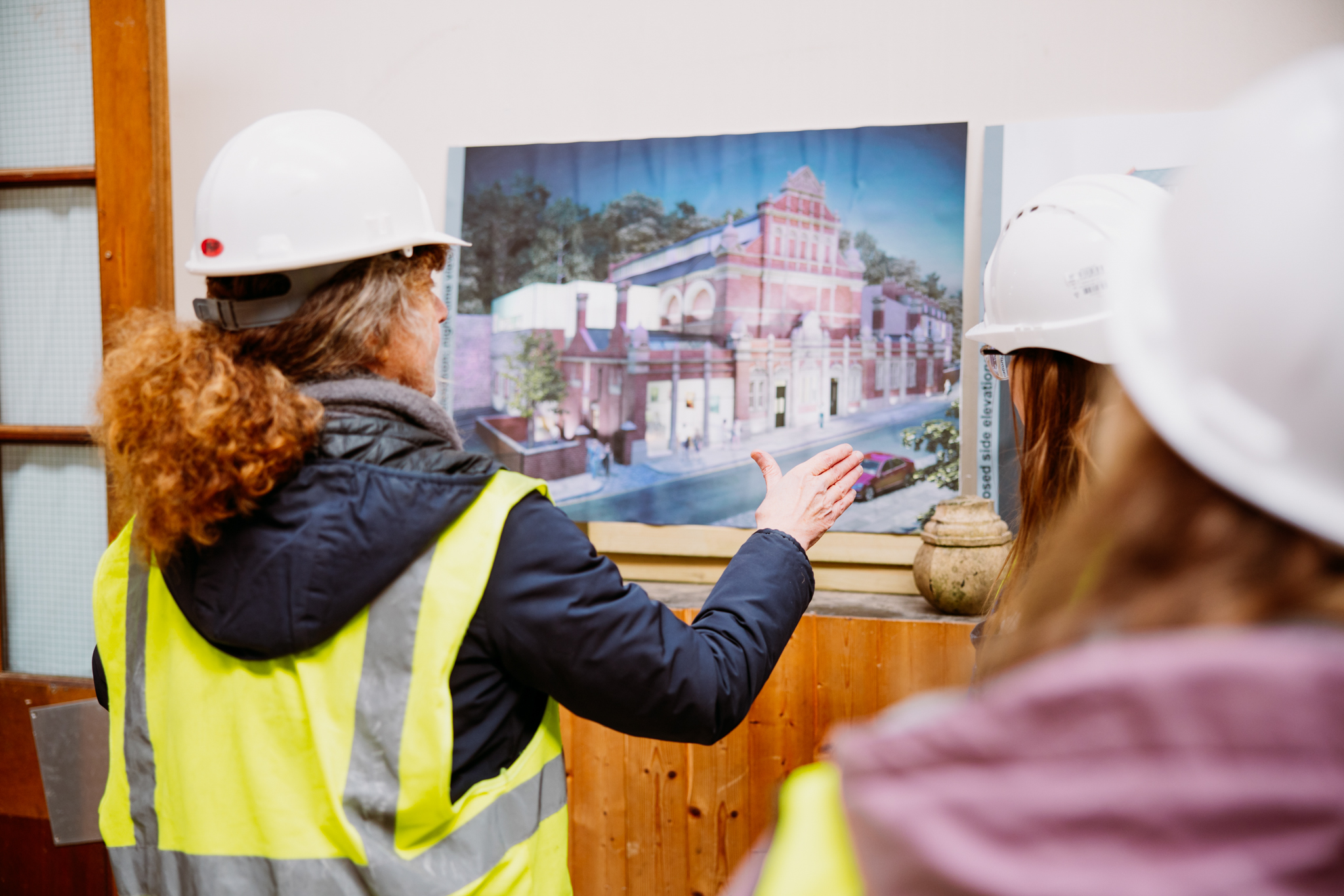A photograph of a woman showing an artist's impression of a historic building as it might look after renovation.