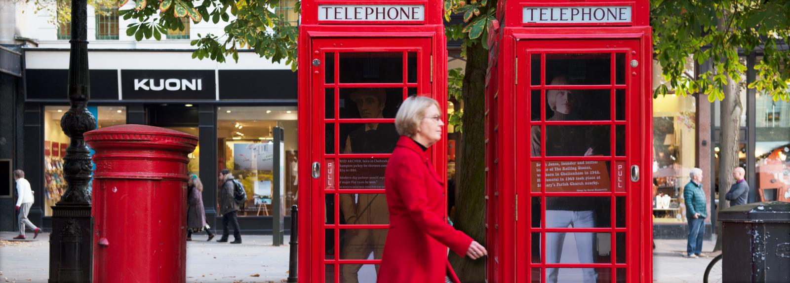 Woman walking past telephone kiosks in Cheltenham