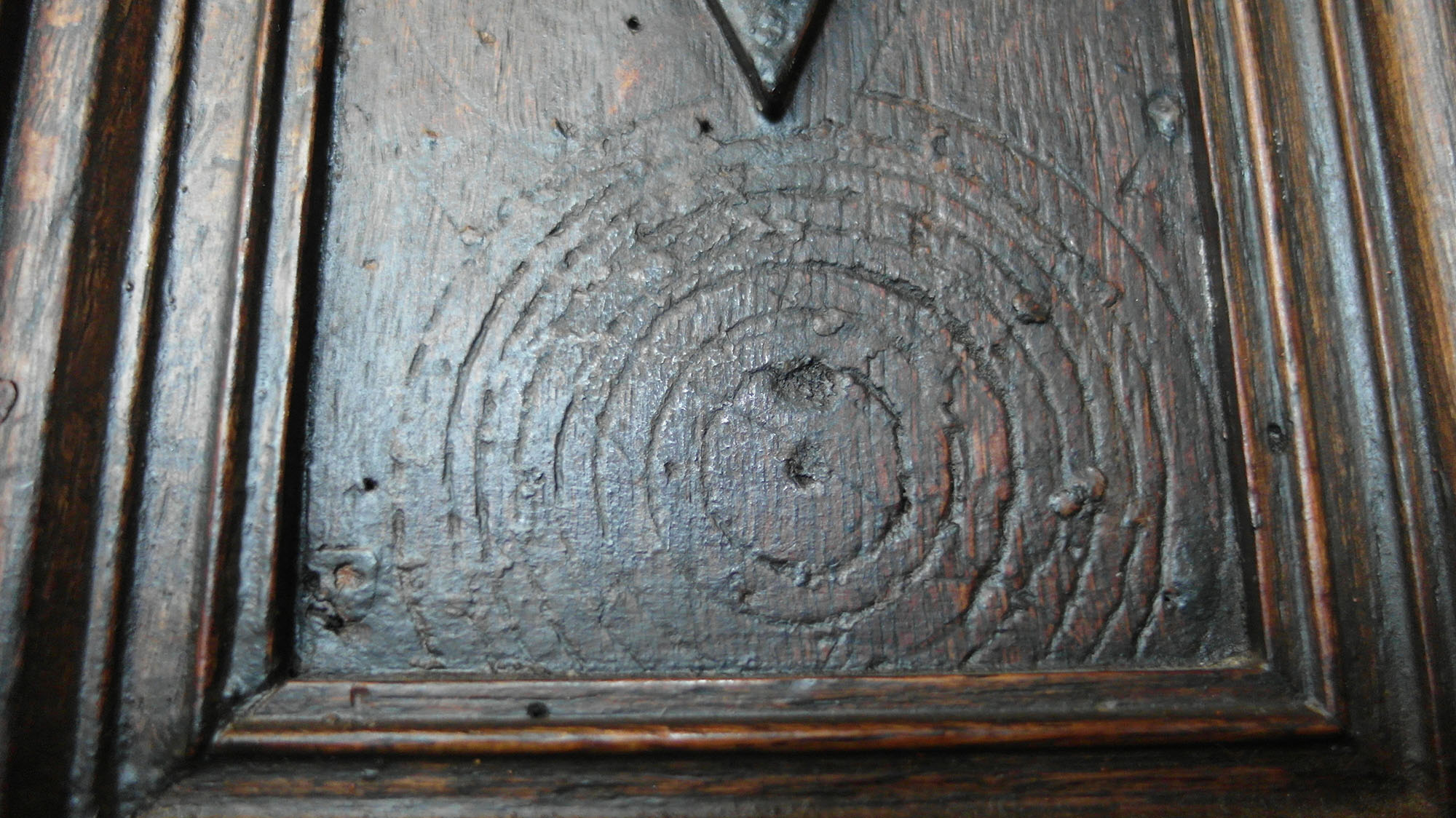 Concentric circles scribed into panelling beside a fireplace