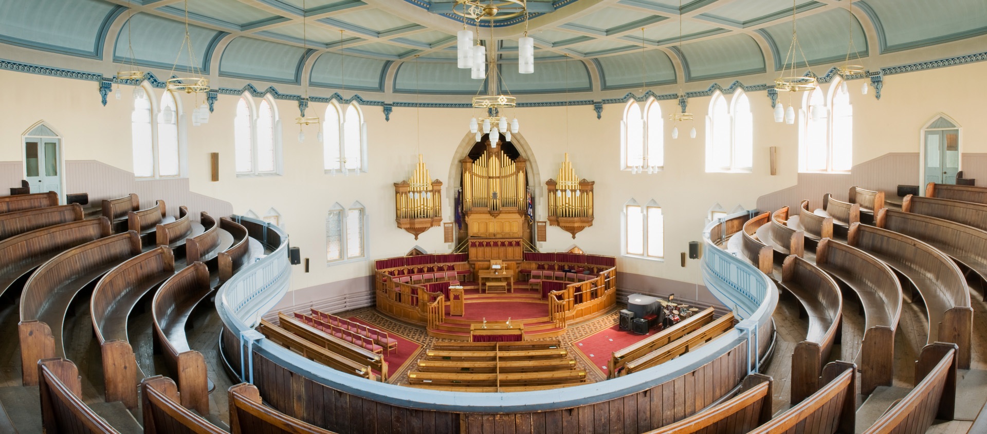 Interior, first floor, showing curved pews on first floor, straight pews on ground floor with organ pipes and central pulpit.