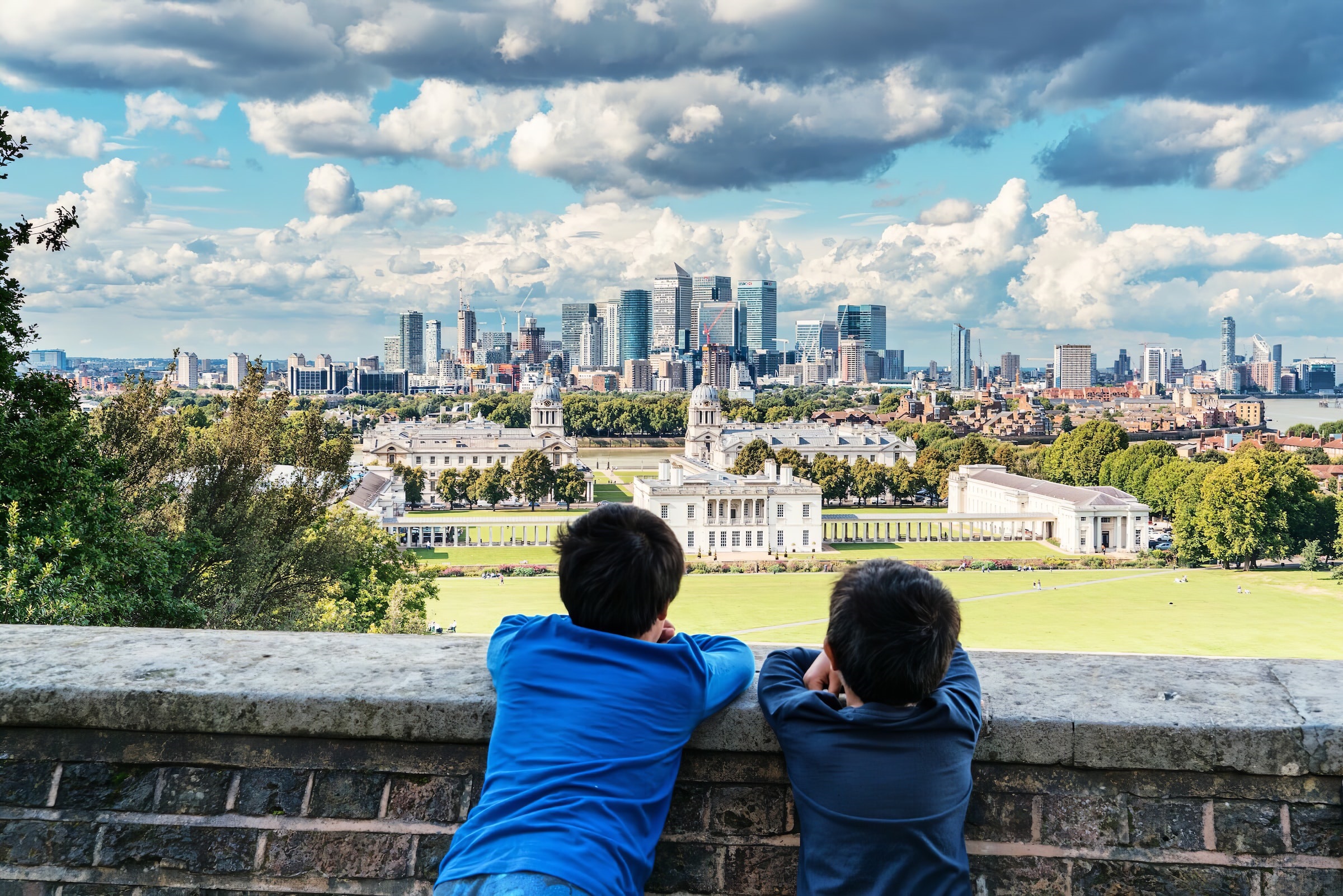 Two boys leaning on a wall overlooking the London city skyline