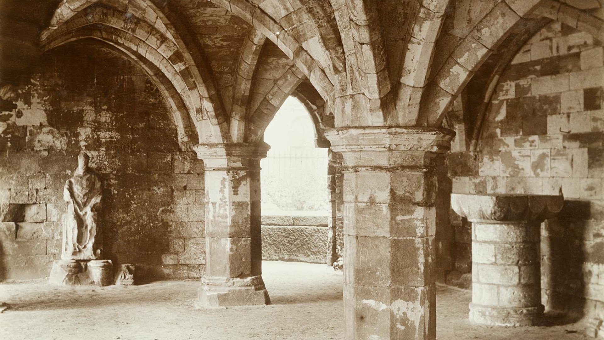 A view of the undercroft of St Leonard's Hospital, York with a statue of a seated figure adjacent to the wall