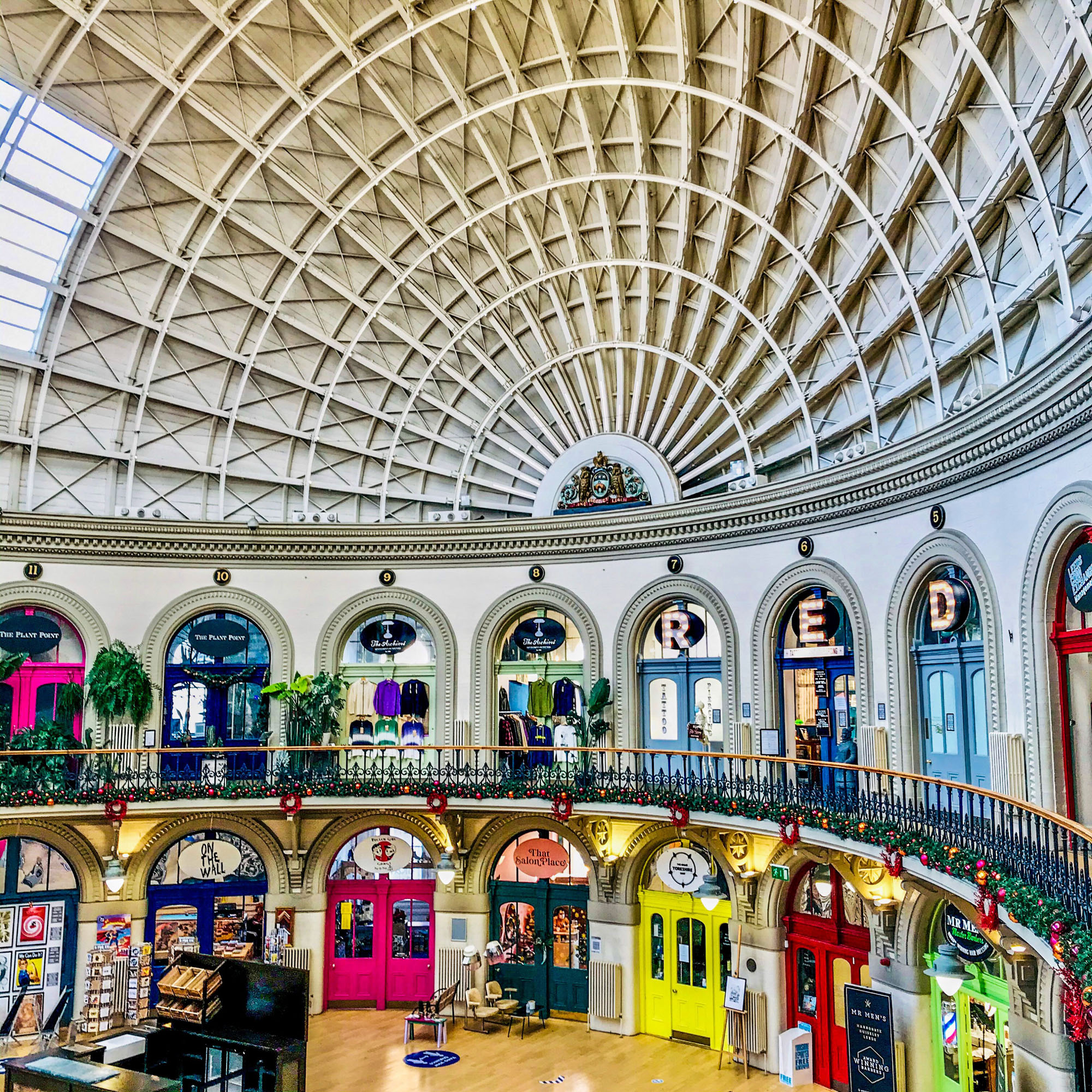 A view from the first floor balcony looking across the open space of the Corn Exchange, with brightly coloured shopfronts beneath the dome.