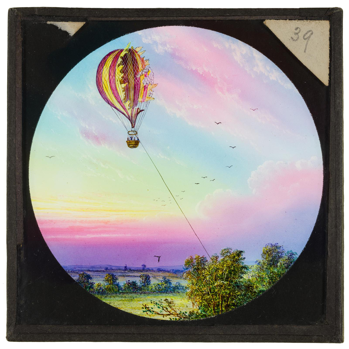 A hand-coloured slide of an engraving showing a tethered balloon which has torn in flight, with a sunrise behind