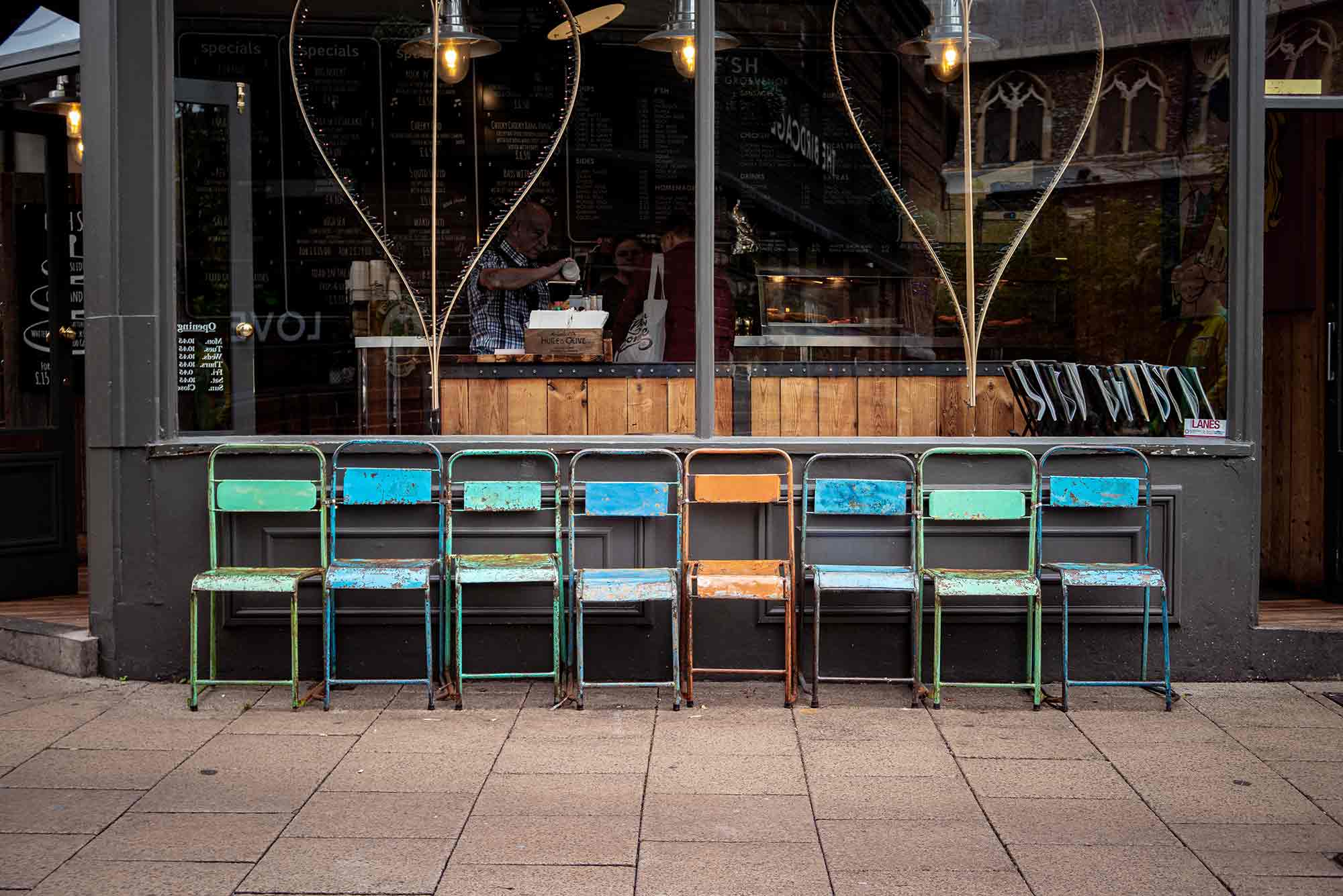 A row of metal chairs in front of a shop window