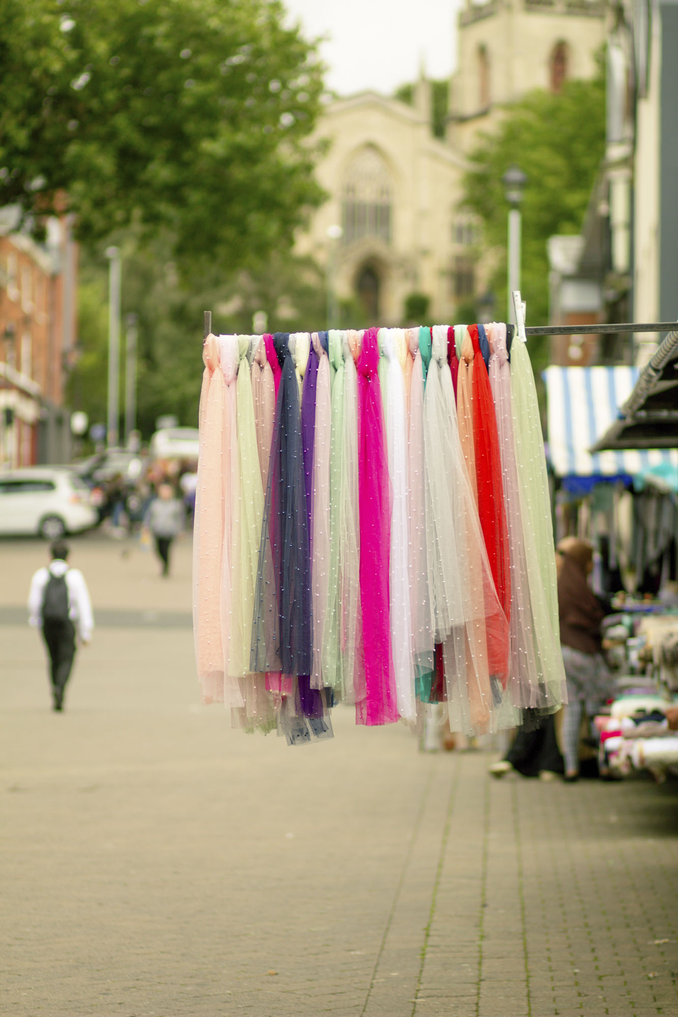 A rail of colourful material on display outside a market stall.