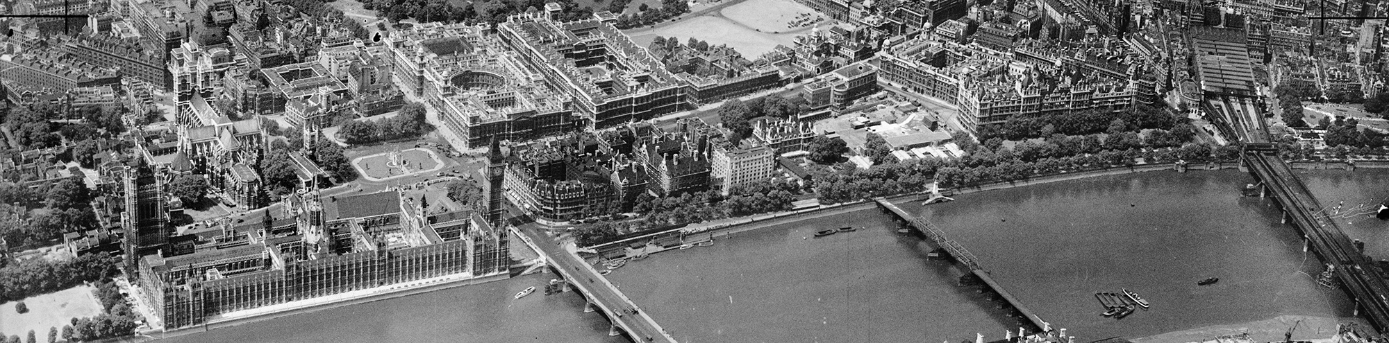 Black and white aerial photo of the Houses of Parliament and River Thames in London.