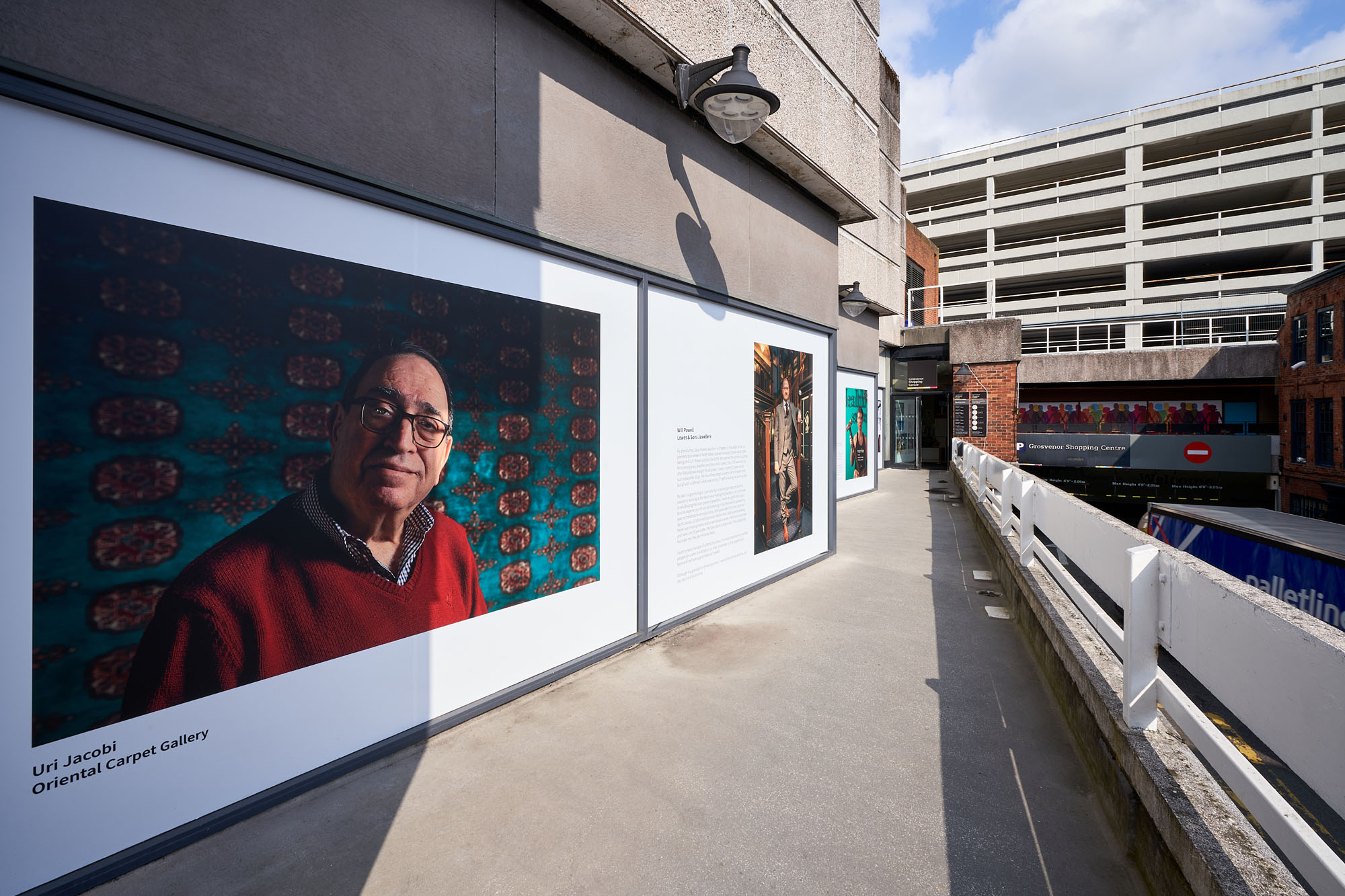 Portrait of a man printed on an external window of Grosvenor Shopping Centre in Chester. The windows and images displayed are on a balcony looking down onto the street below.