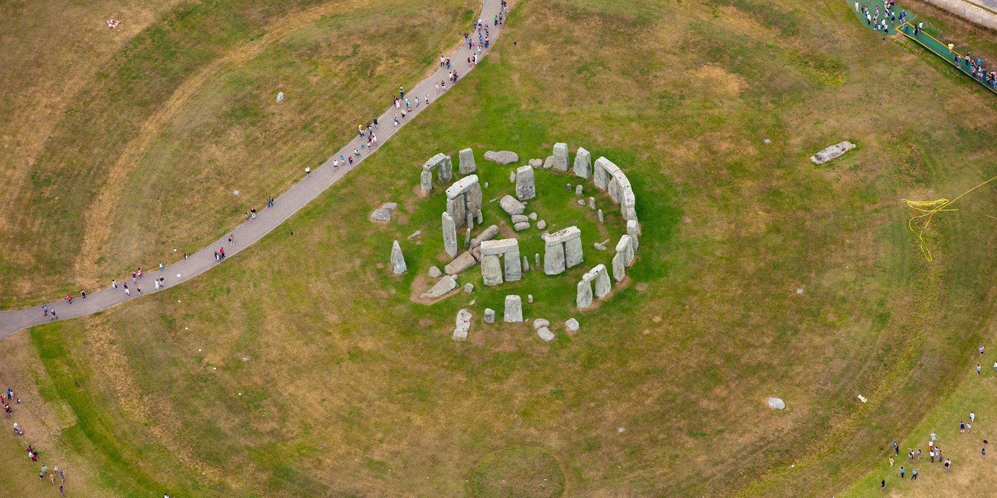 An aerial view of the rocks of Stonehenge. Visitors walking round are tiny in comparison.